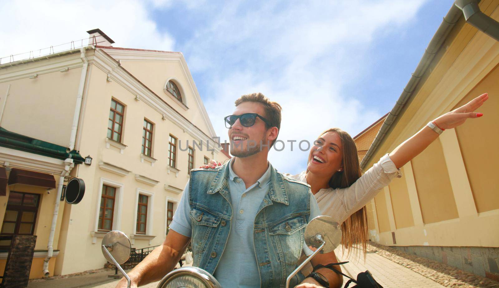 happy young couple riding scooter in town. Handsome guy and young woman travel. Adventure and vacations concept.