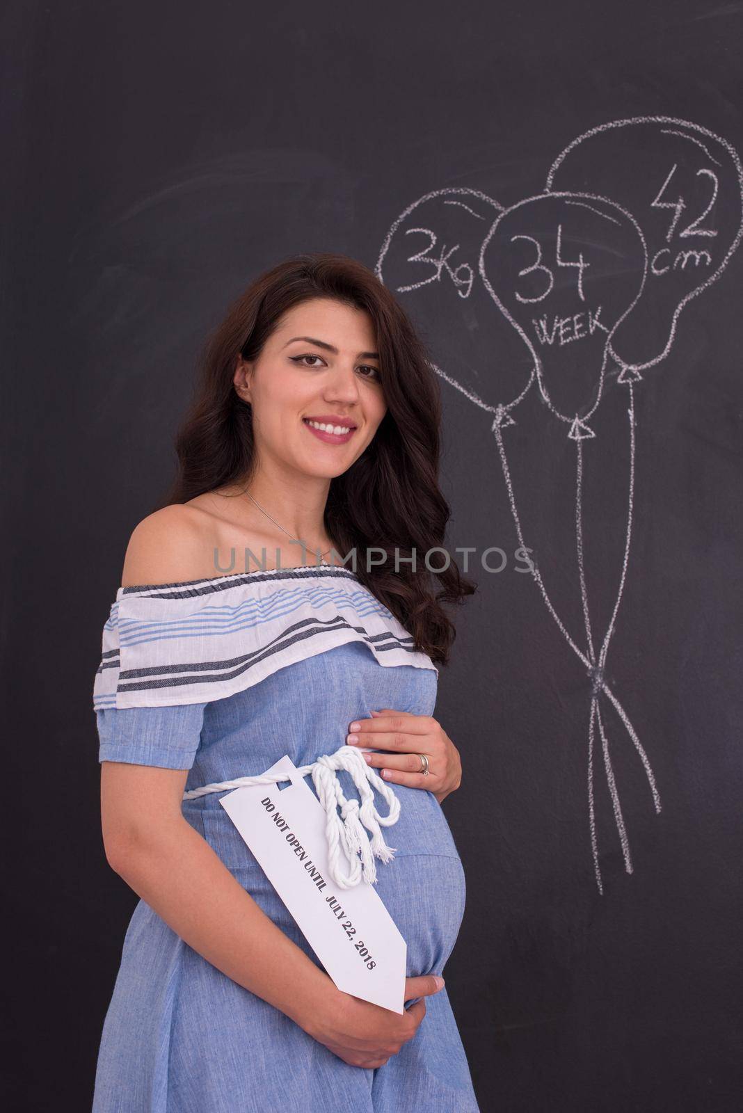 Portrait of pregnant woman in front of black chalkboard by dotshock