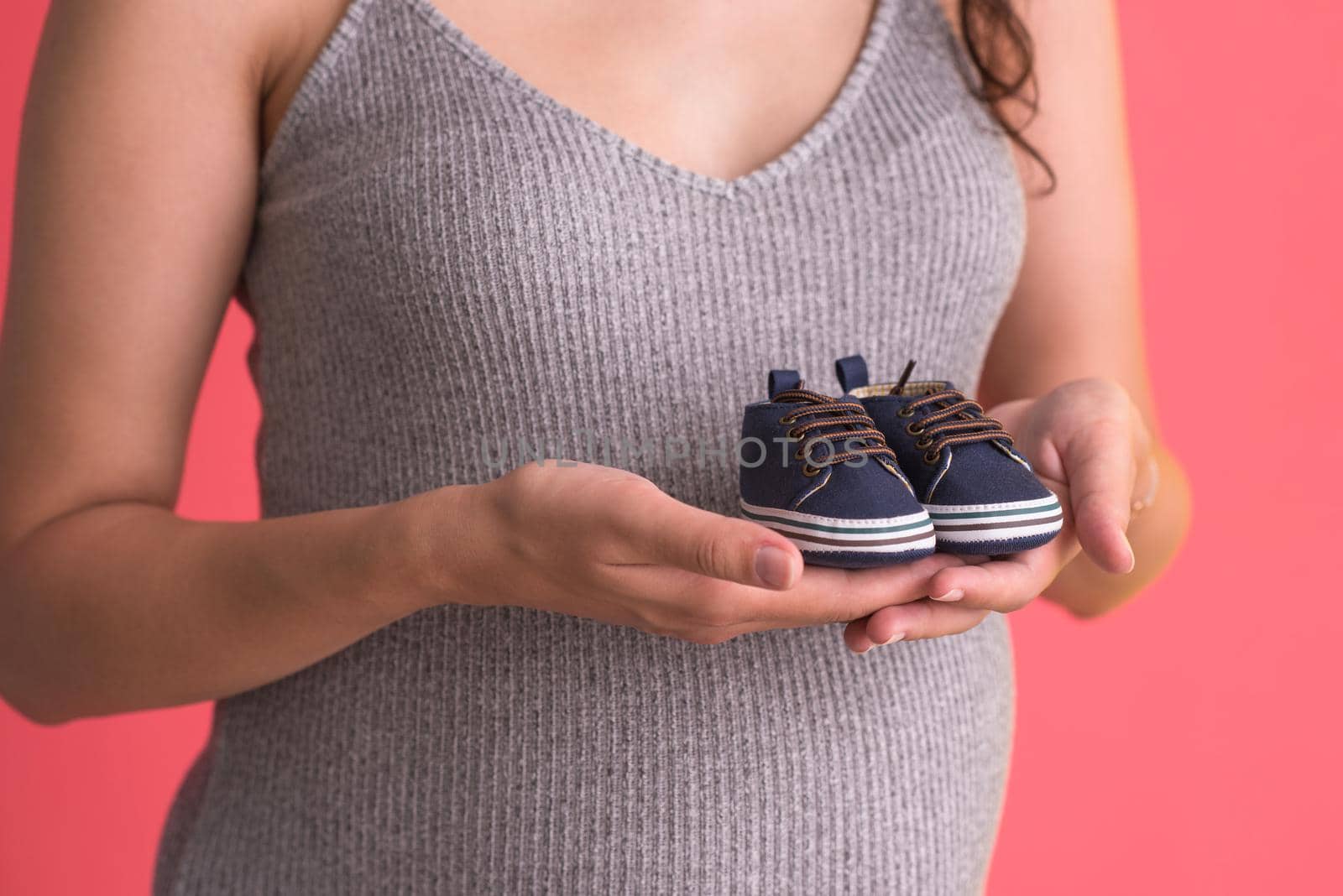 pregnant woman holding a tiny baby shoes by dotshock