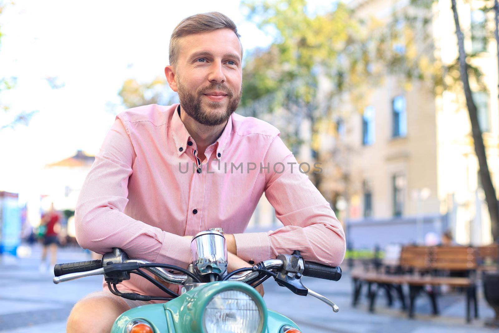 Handsome man posing on a scooter in a vacation context. Street fashion and style
