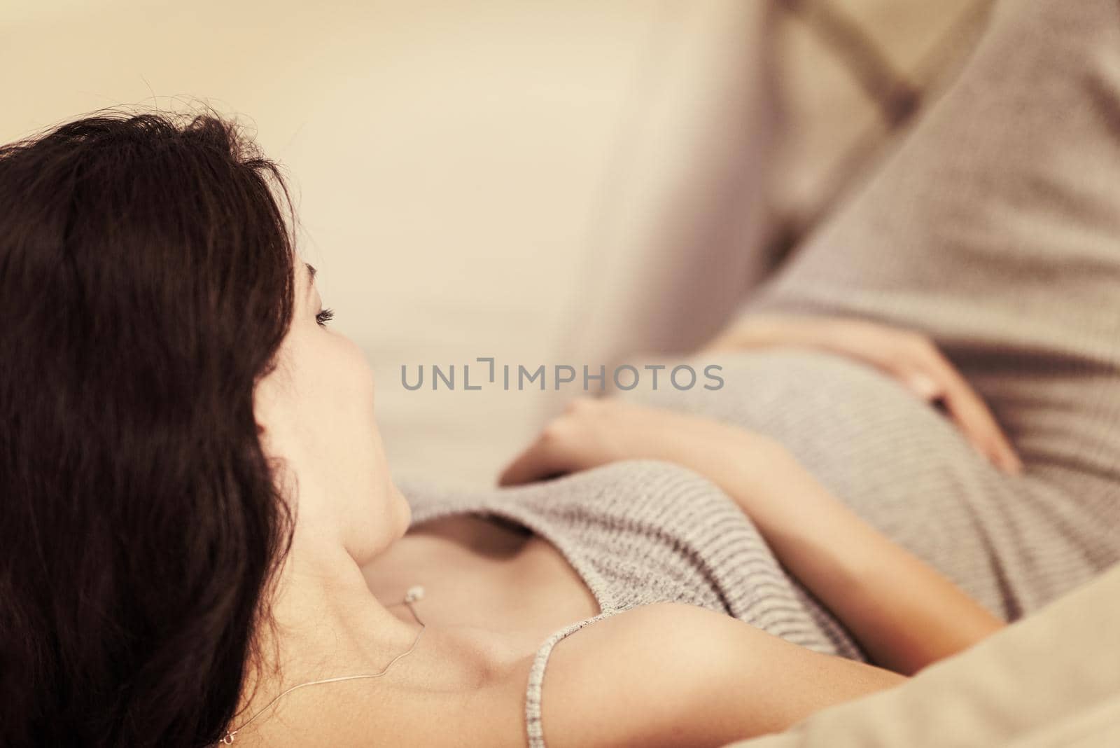 pregnant woman sitting on sofa at home by dotshock
