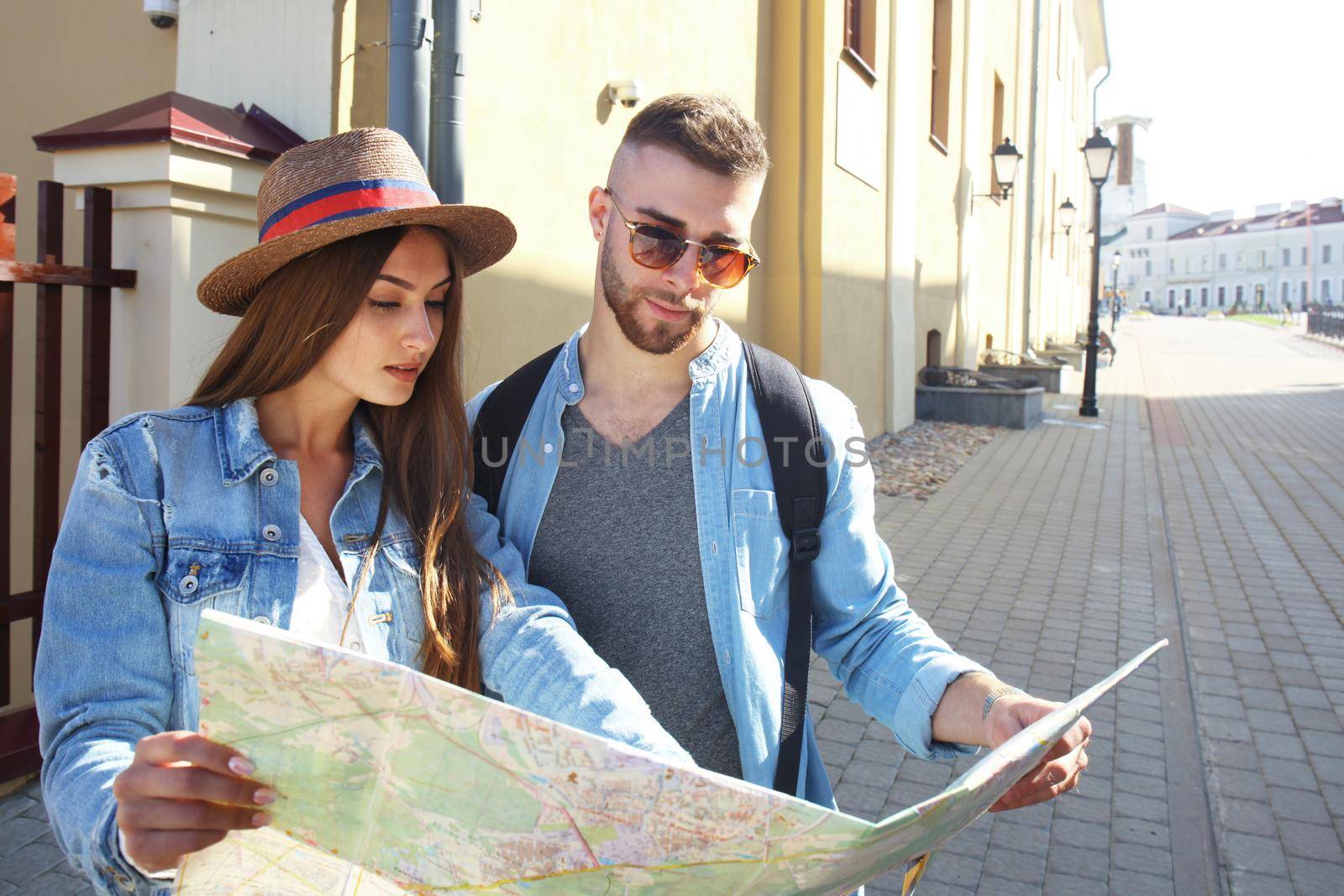 Happy couple walking outdoors sightseeing and holding a map.