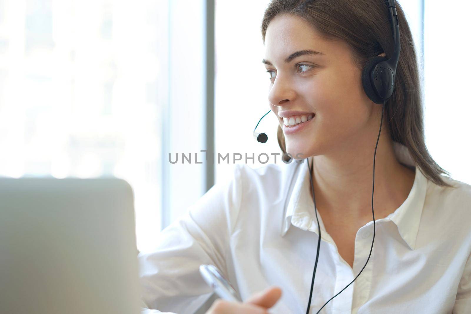 Female customer support operator with headset and smiling.