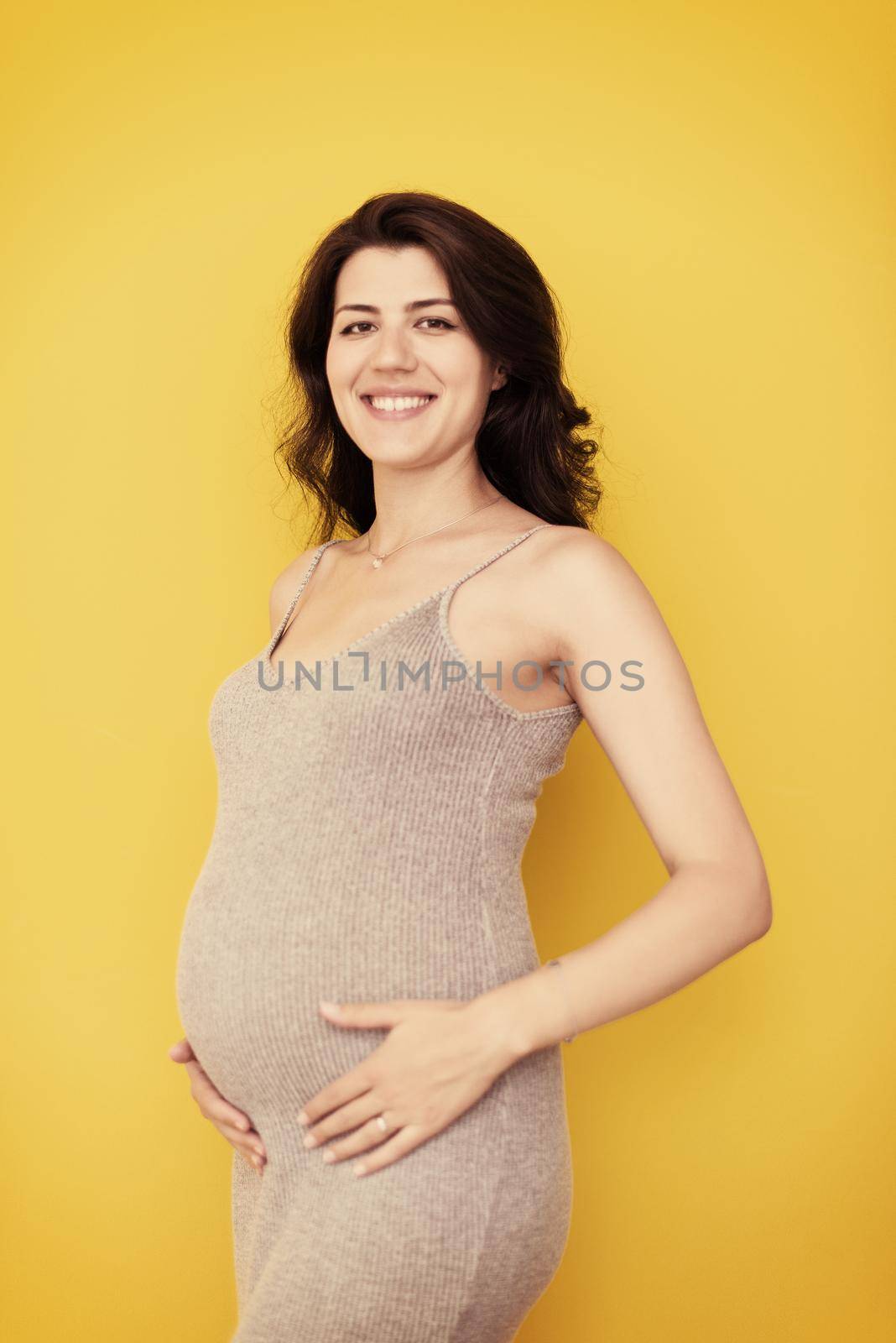 Portrait of pregnant woman over yellow background by dotshock