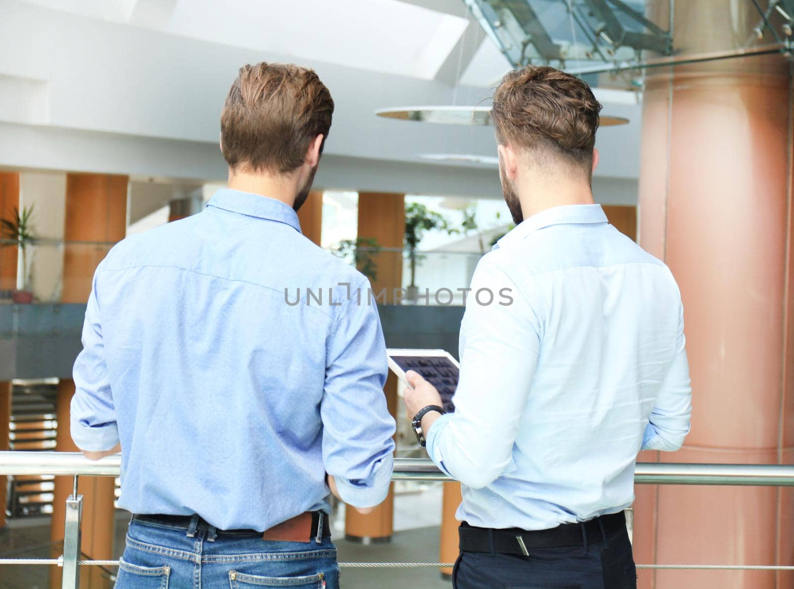 Group of young modern people in smart casual wear having a brainstorm meeting while standing in the creative office.