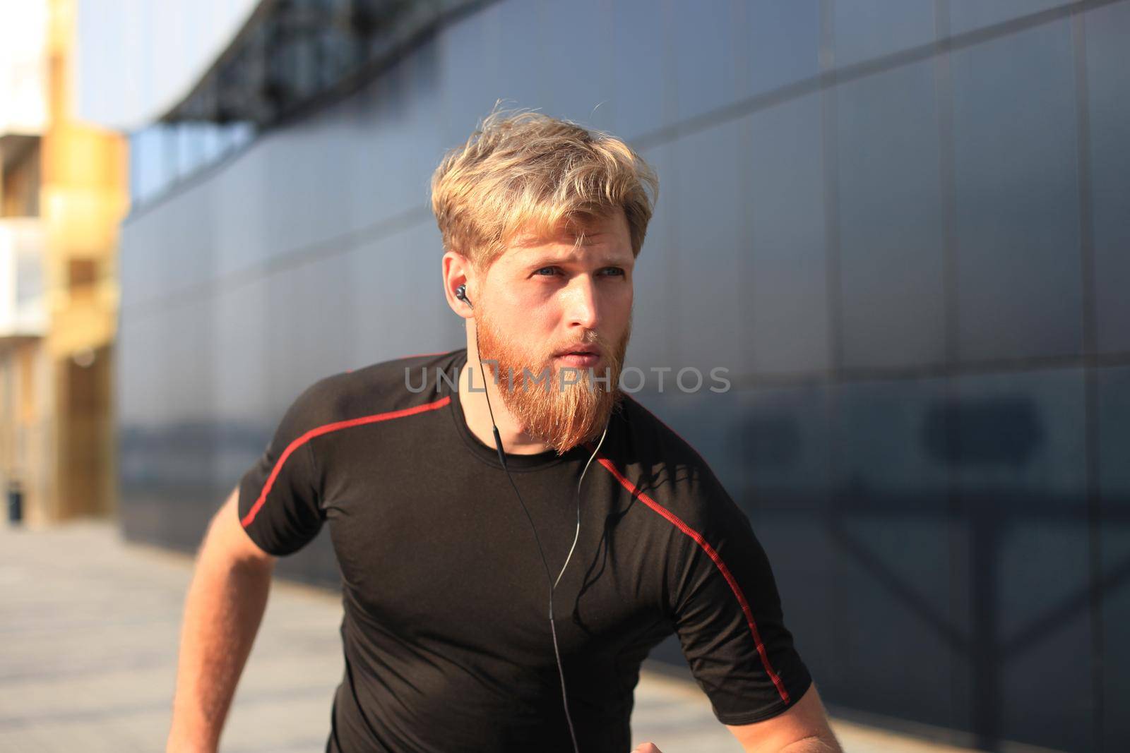 Fit athlete. Handsome adult man running outdoors to stay healthy, at sunset or sunrise. Runner