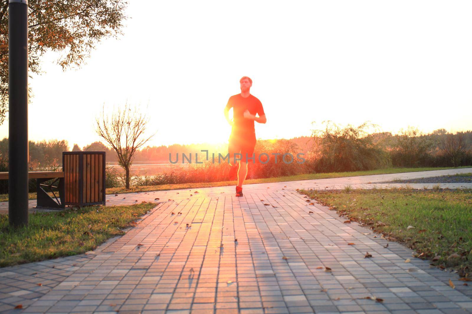 Fit athlete. Handsome adult man running outdoors to stay healthy, at sunset or sunrise. Runner