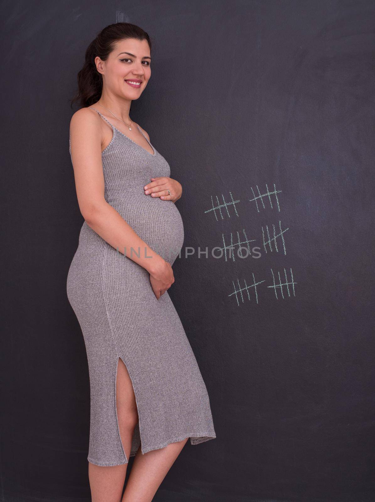 Portrait of pregnant woman in front of black chalkboard by dotshock