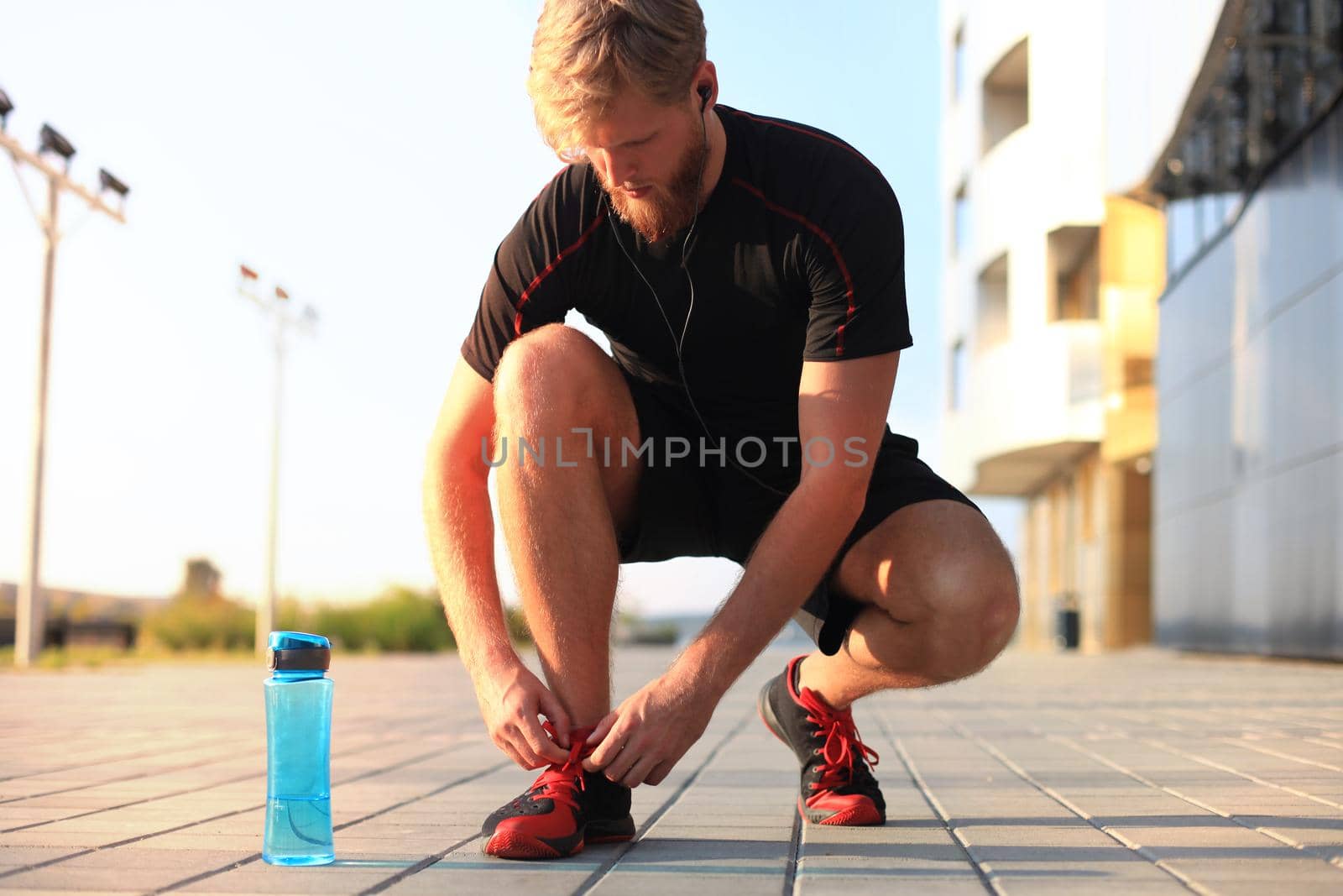 Young handsome athlete tying her laces outdoors