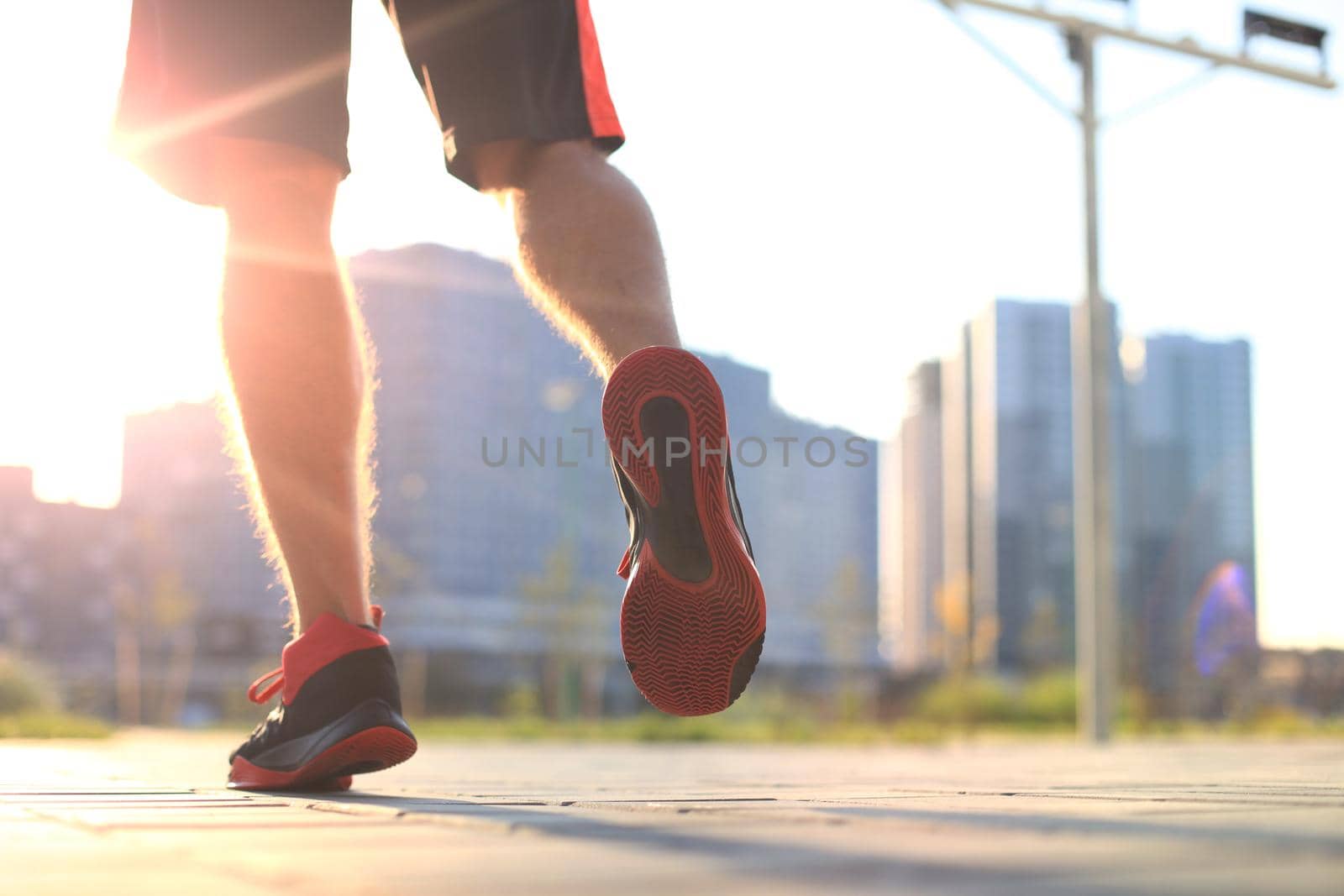 African man legs running while exercising outdoors, at sunrise or sunset.