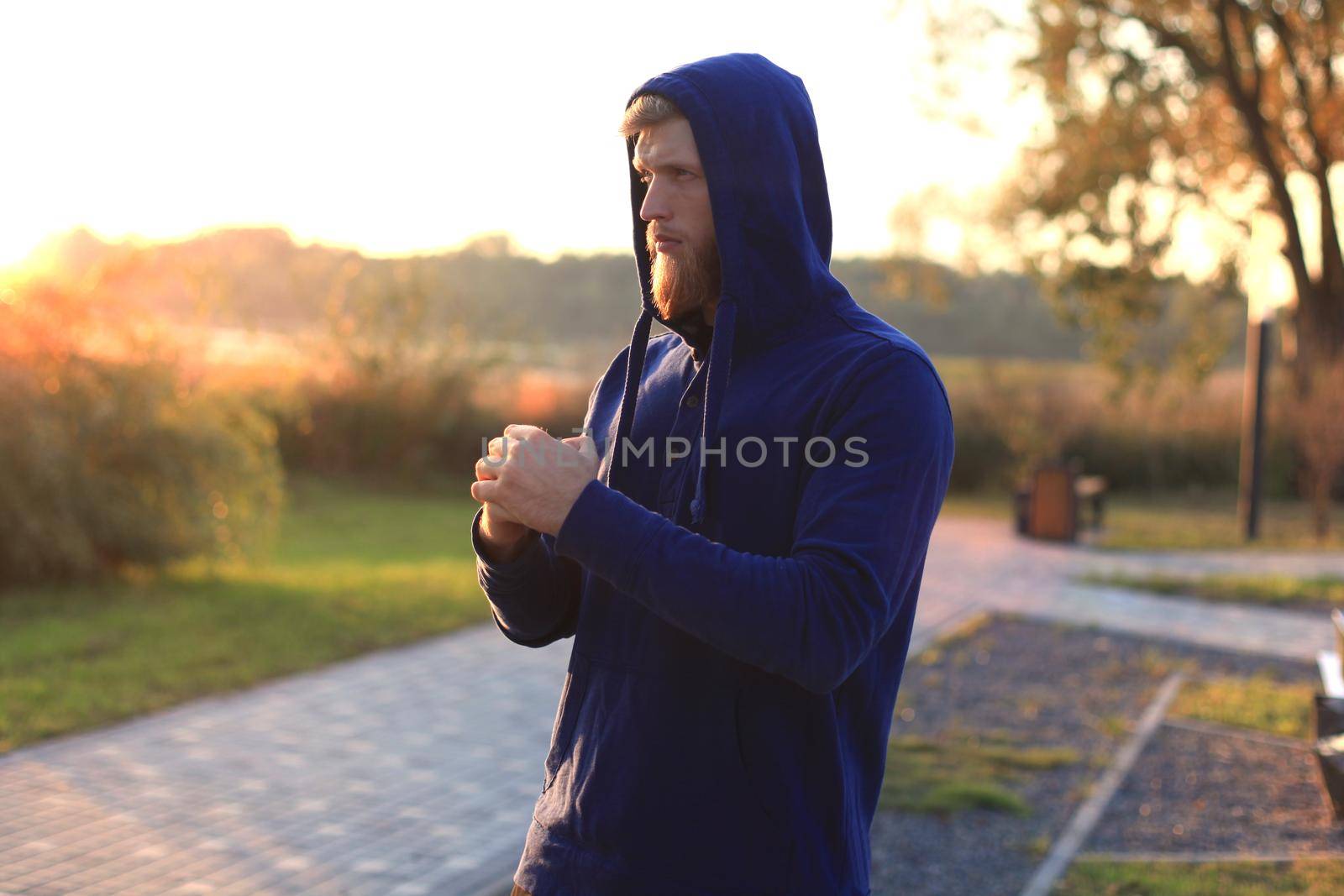 Handsome young man doing stretching exercises before running while standing outdoors