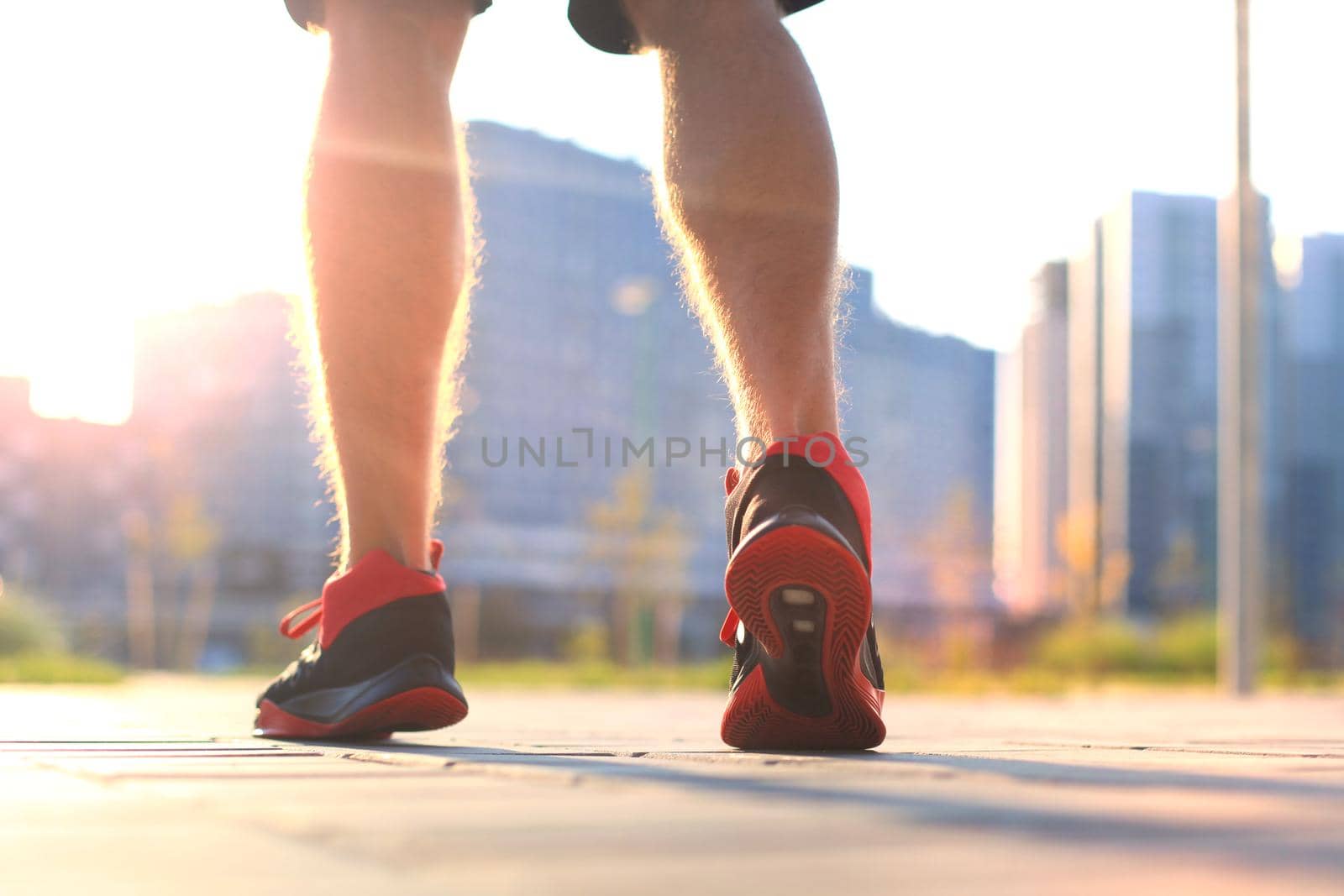 African man legs running while exercising outdoors, at sunrise or sunset.