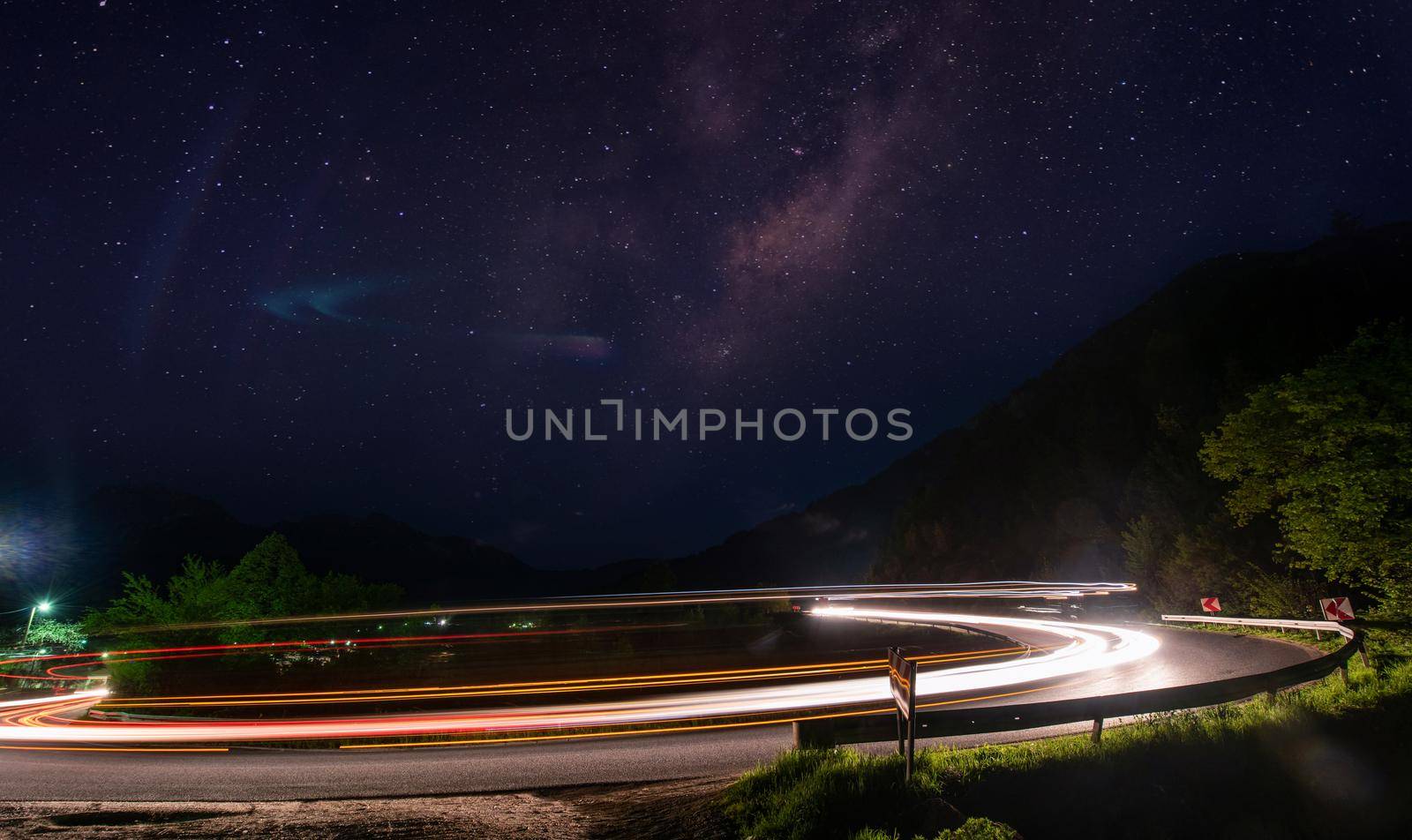 vegicle light trails in night on busy countryroad curve  long exposure