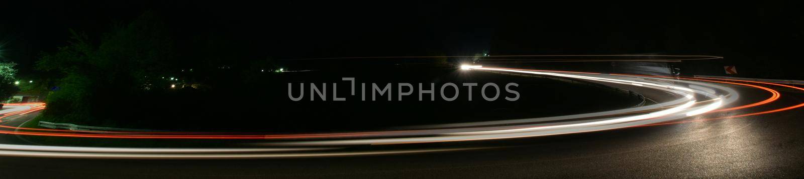 vegicle light trails in night on busy countryroad curve  long exposure