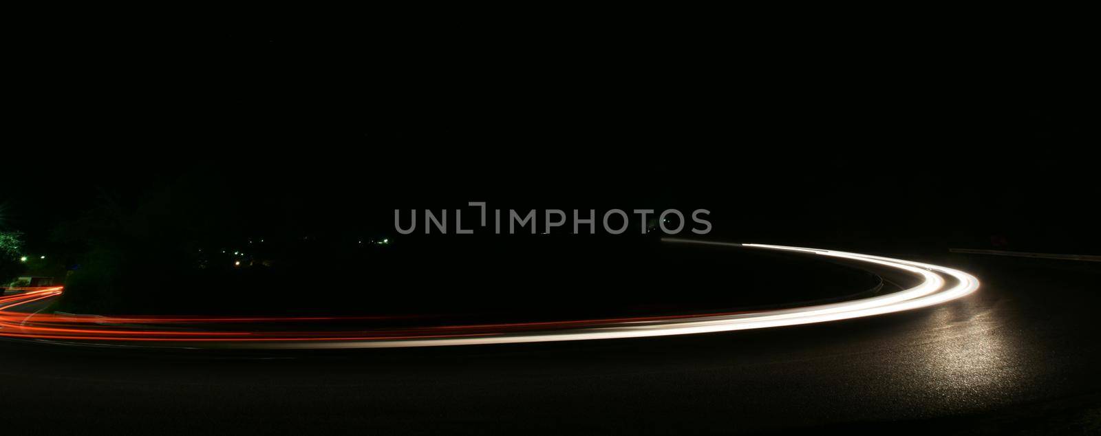 vegicle light trails in night on busy countryroad curve  long exposure