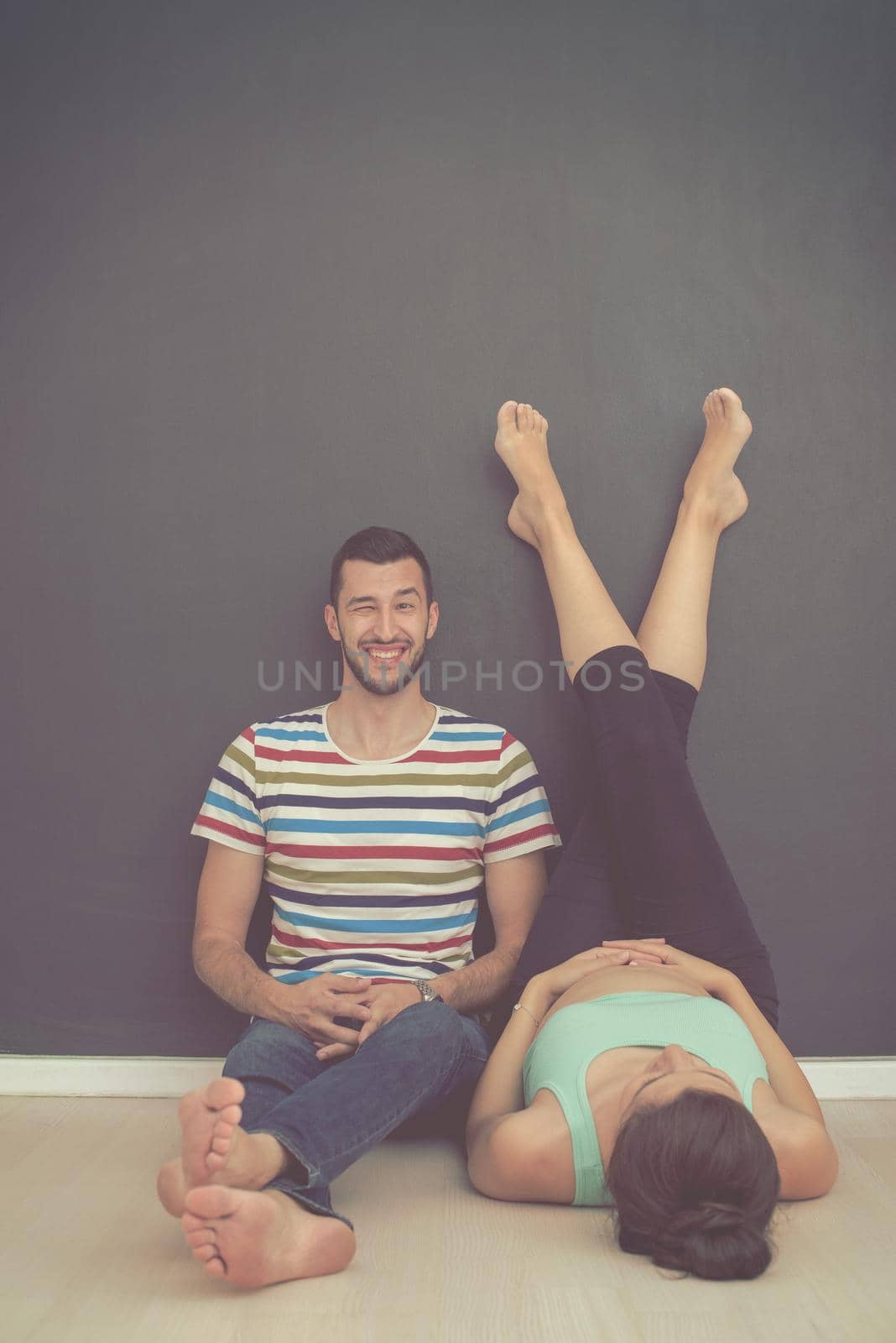happy pregnant couple relaxing in front of black chalkboard on the floor at home