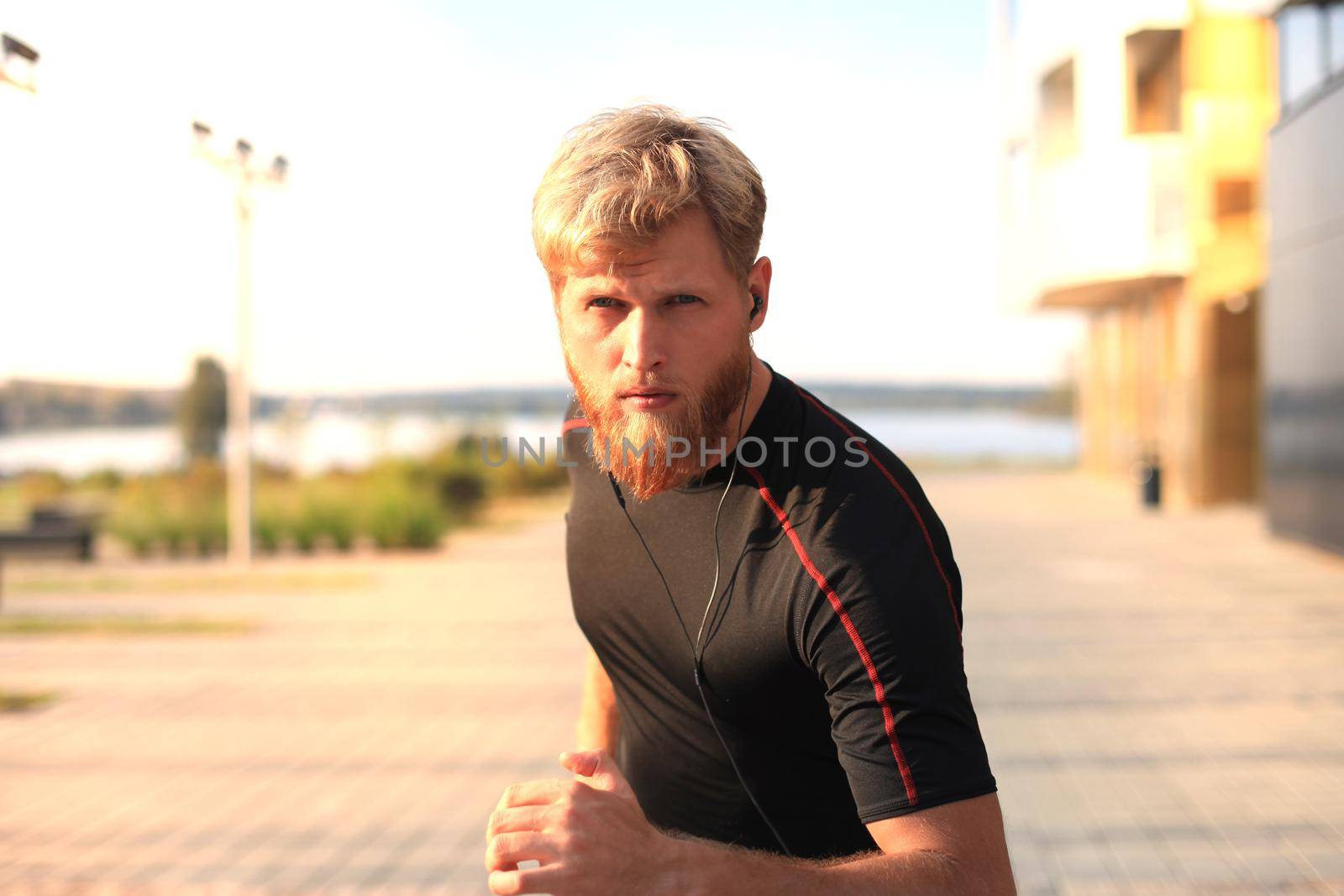 Fit athlete. Handsome adult man running outdoors to stay healthy, at sunset or sunrise. Runner by tsyhun