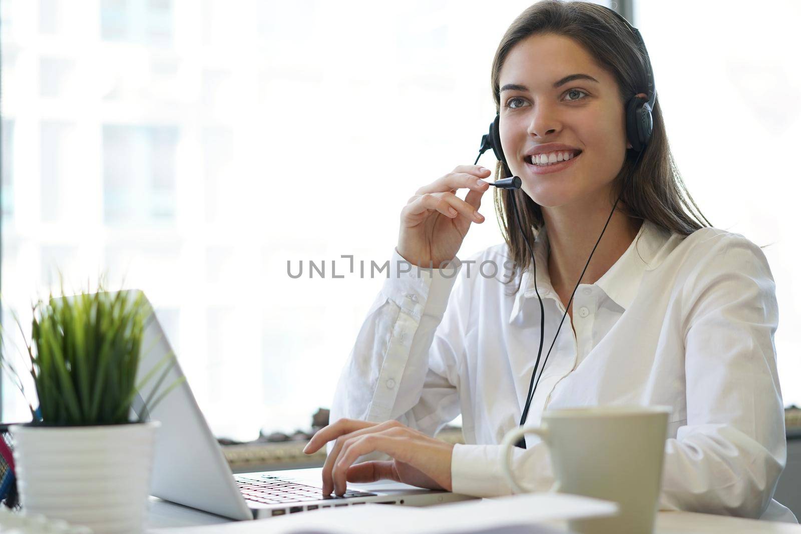 Female customer support operator with headset and smiling.