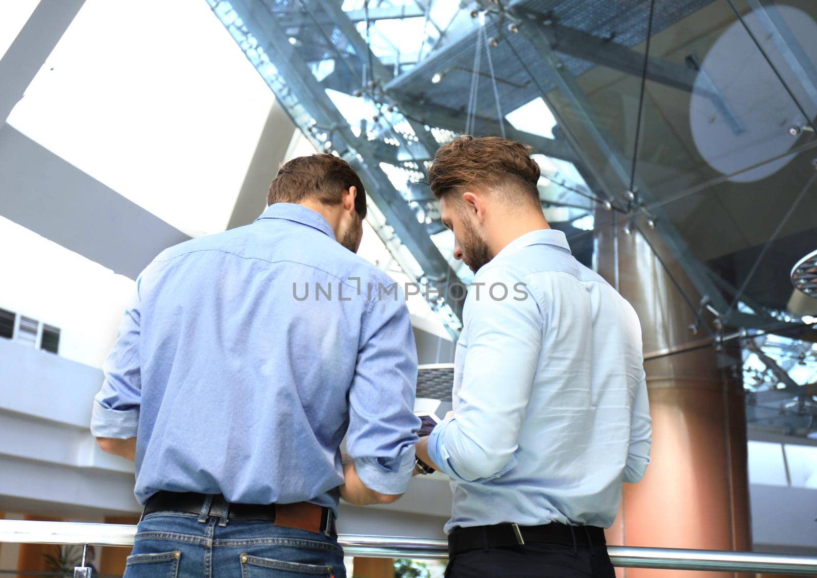 Group of young modern people in smart casual wear having a brainstorm meeting while standing in the creative office.