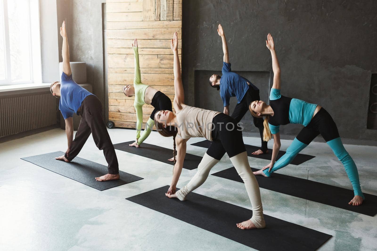Young women and men in yoga class, stretching and balance exercises. Healthy lifestyle in fitness club, copy spae