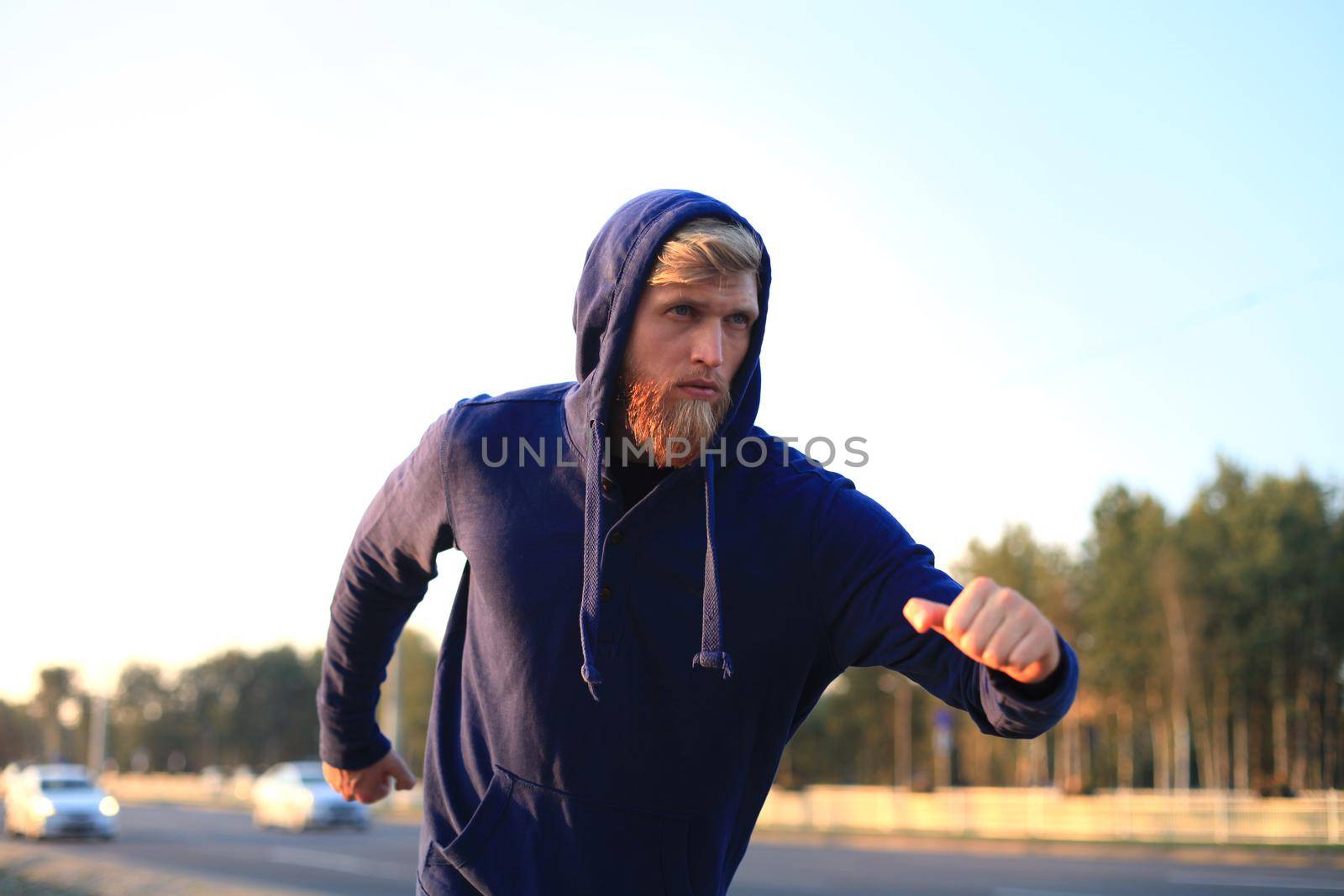 Fit athlete. Handsome adult man running outdoors to stay healthy, at sunset or sunrise. Runner