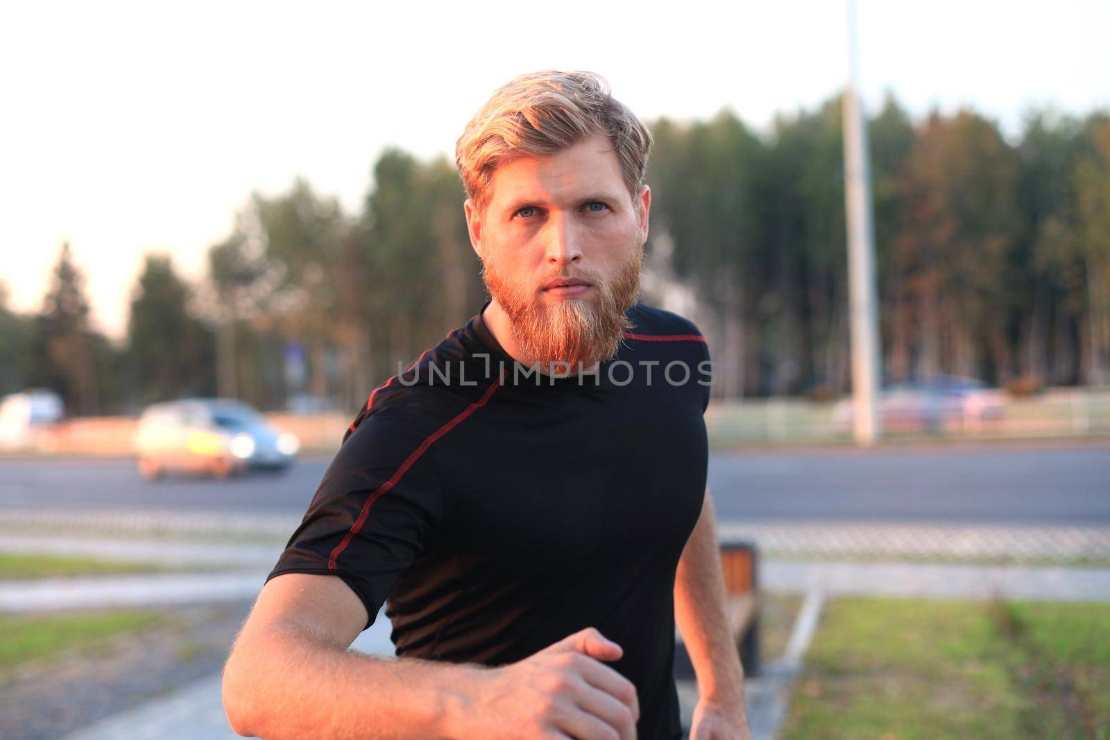 Fit athlete. Handsome adult man running outdoors to stay healthy, at sunset or sunrise. Runner by tsyhun