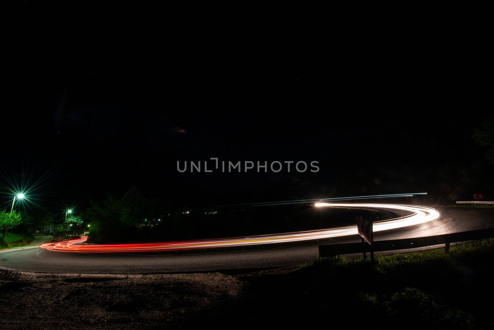 vegicle light trails in night on busy countryroad curve  long exposure