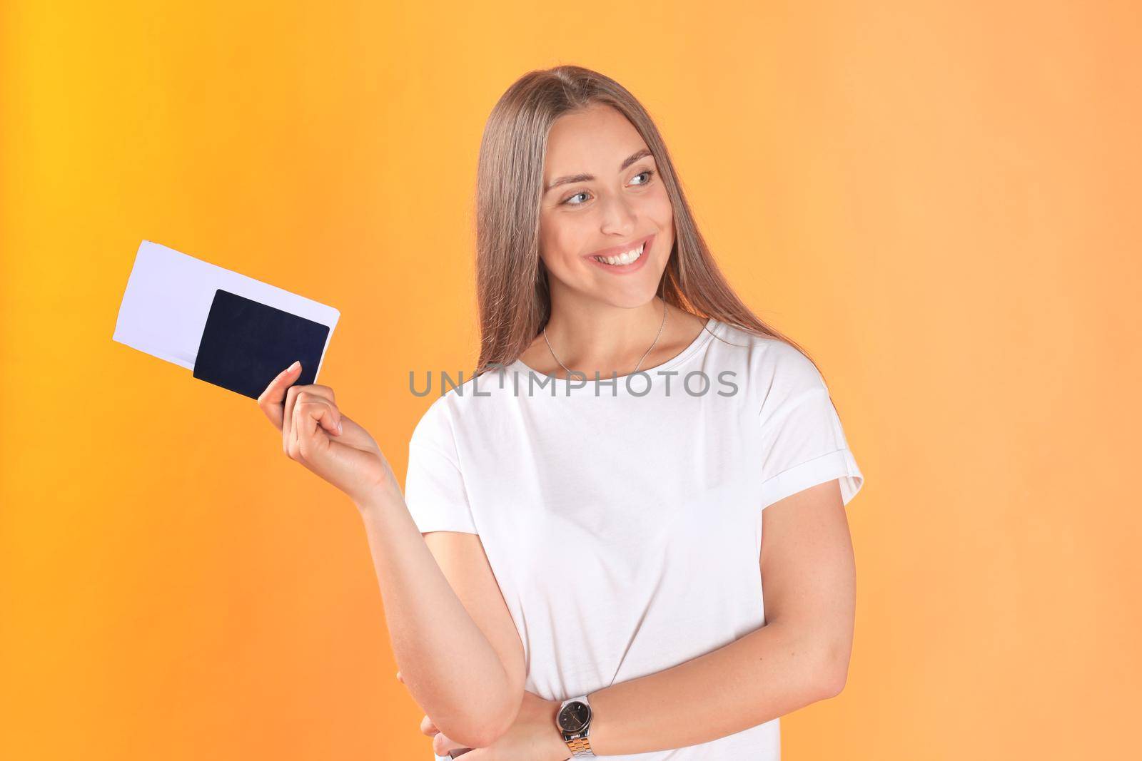 Excited young woman tourist standing isolated on yellow background holding passport with tickets. by tsyhun