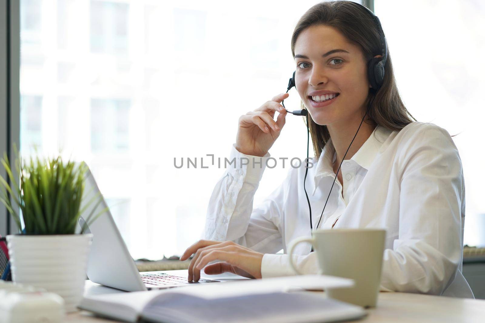 Female customer support operator with headset and smiling.