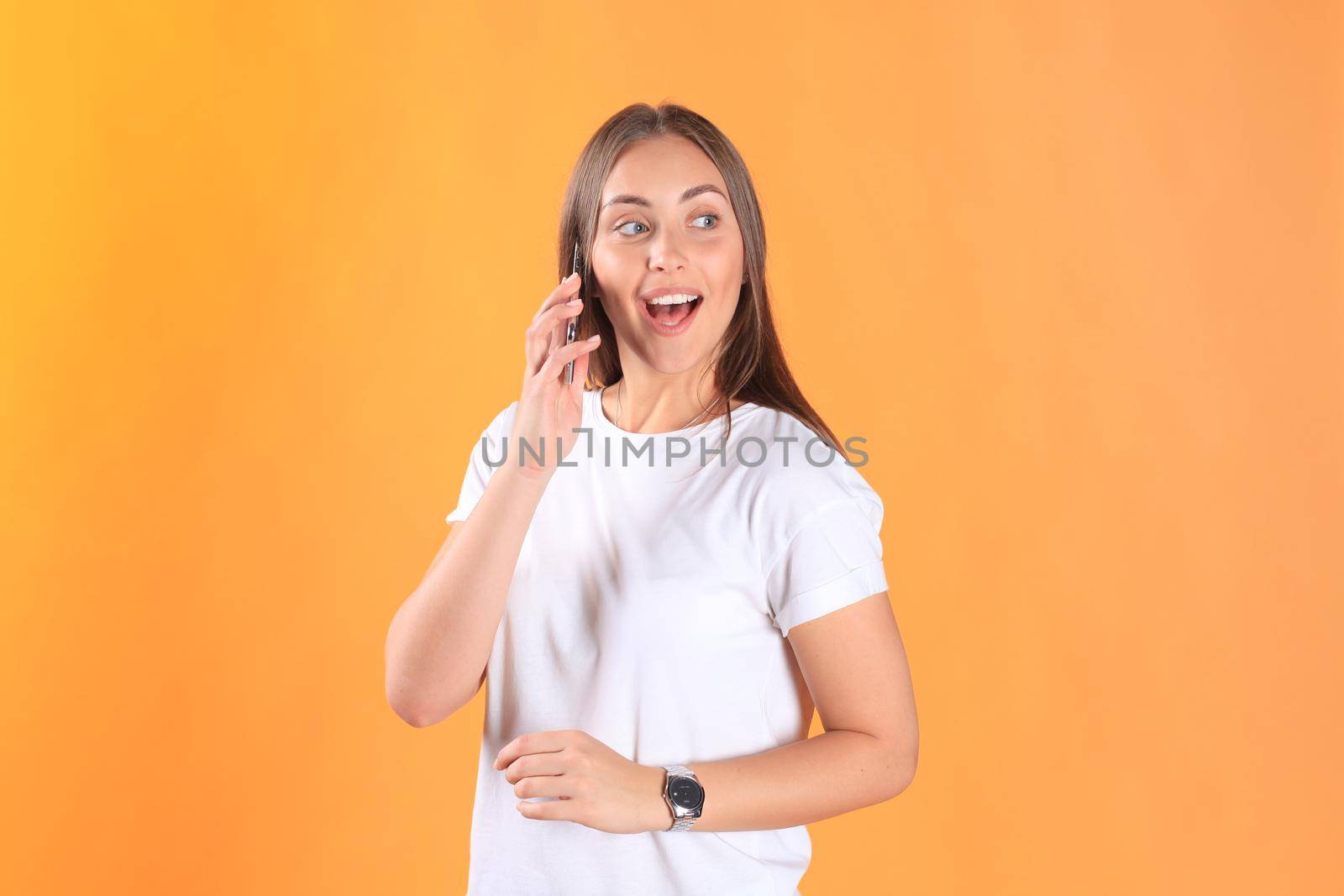 Young woman dressed in basic clothing isolated on yellow background, talking on mobile phone. by tsyhun