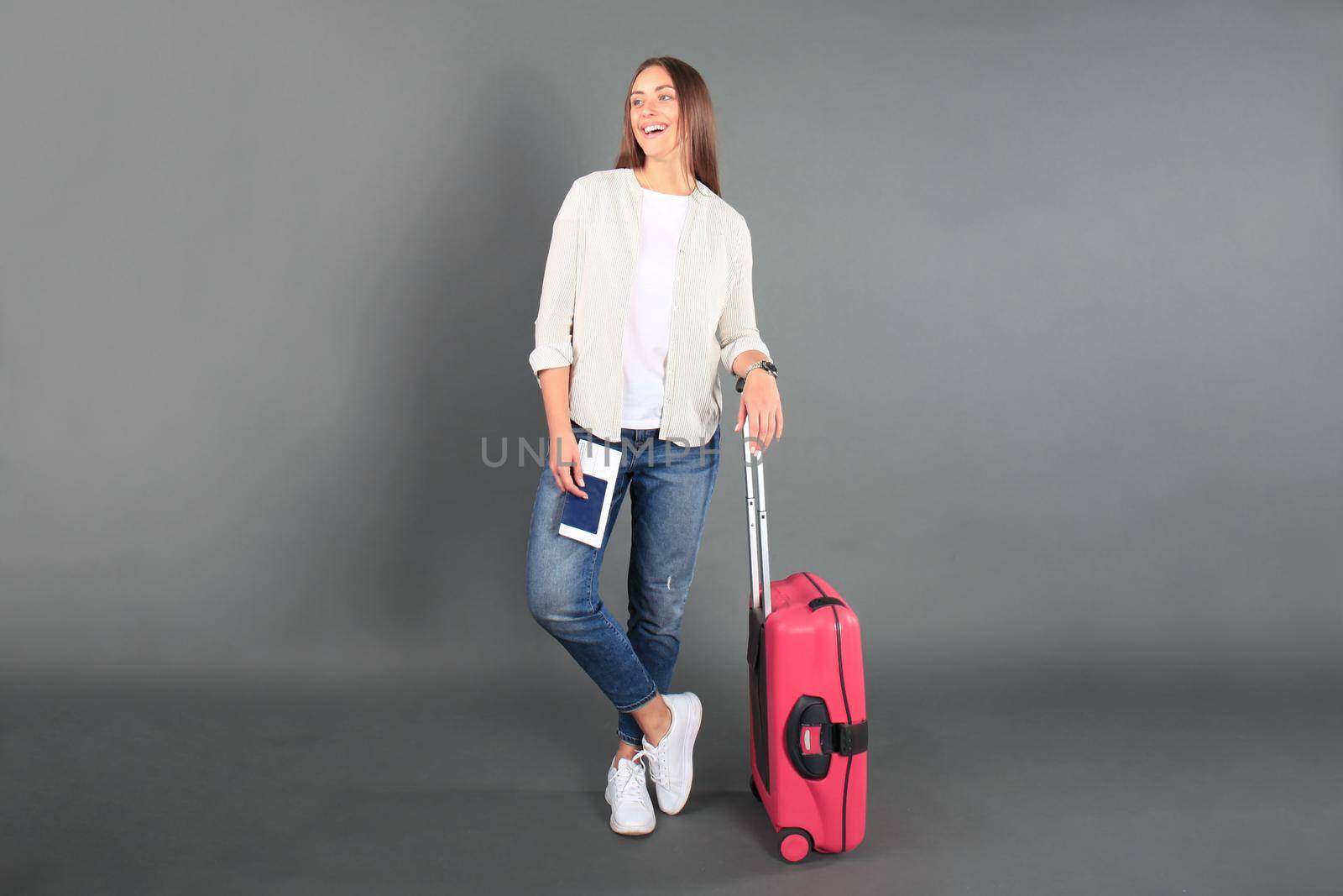 Young tourist girl in summer casual clothes, with sunglasses, red suitcase, passport, tickets isolated grey background.