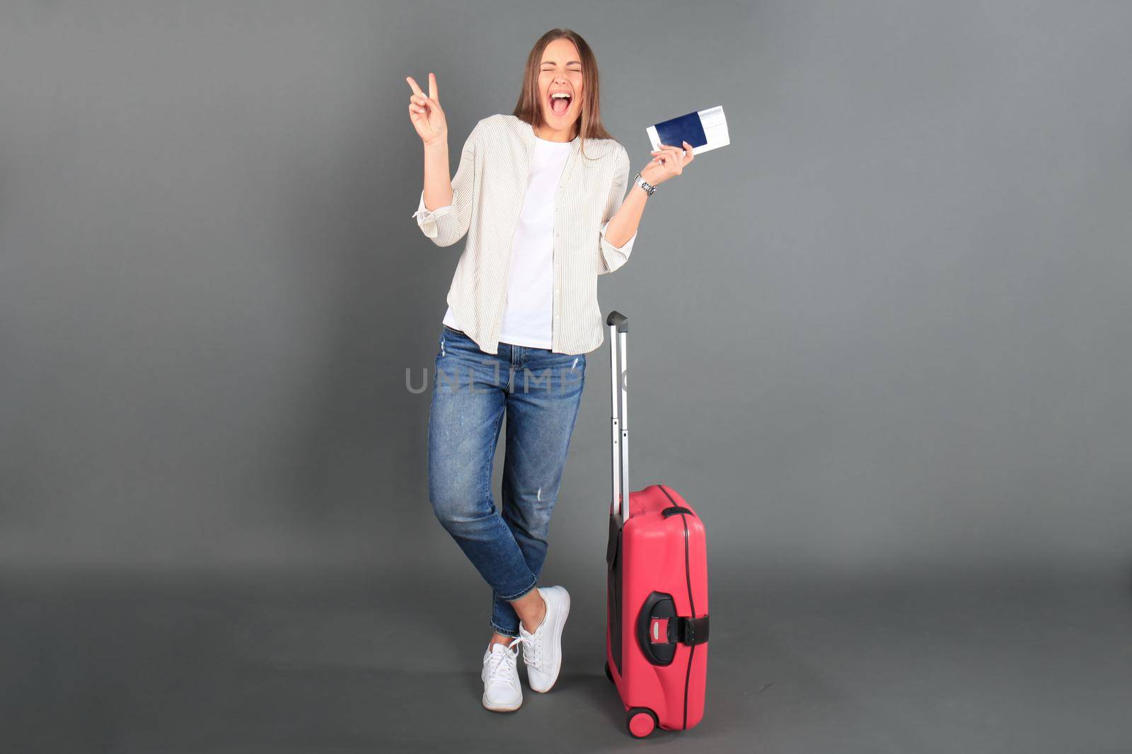 Young tourist girl in summer casual clothes, with sunglasses, red suitcase, passport, tickets isolated grey background. by tsyhun