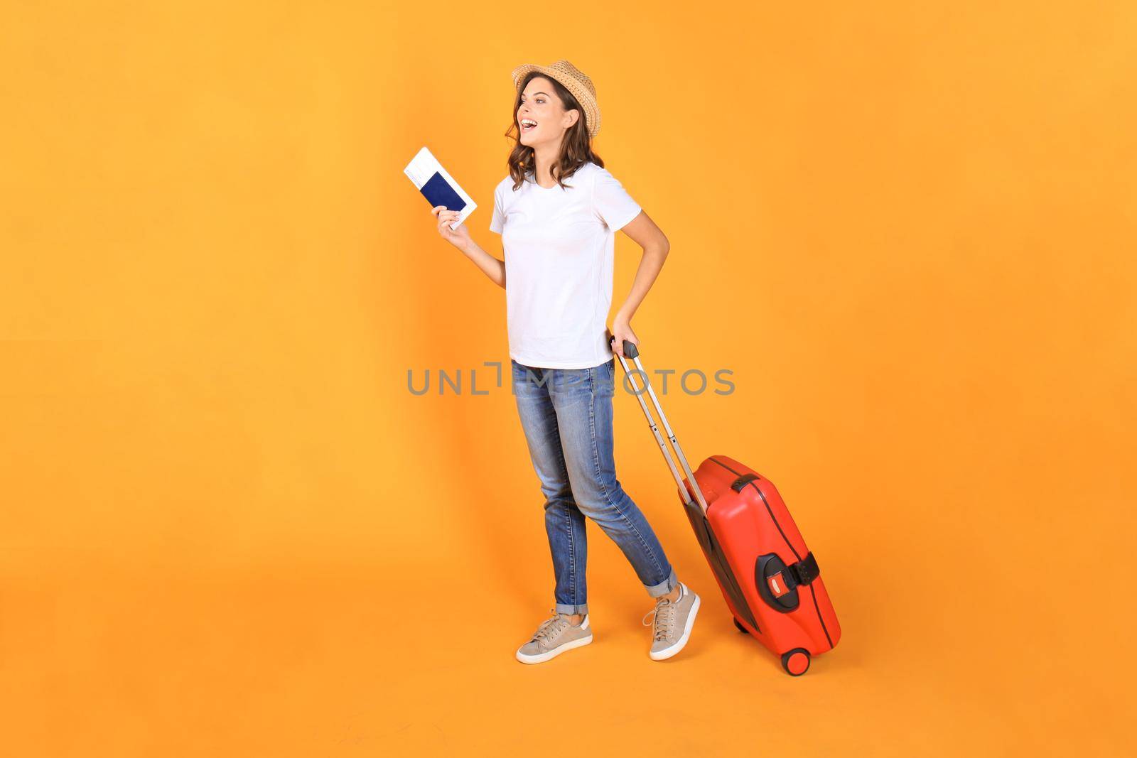 Young tourist girl in summer casual clothes, with red suitcase, passport, tickets isolated on beige background