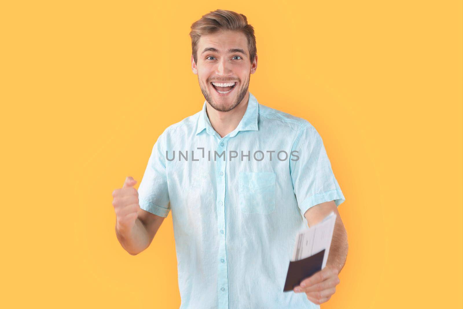 Young man isolated over yellow background holding passport pointing