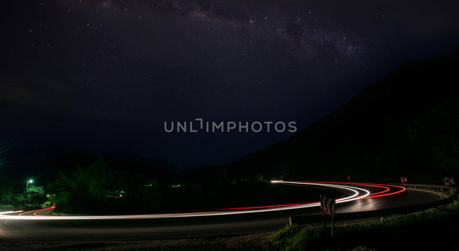 vegicle light trails in night on busy countryroad curve  long exposure