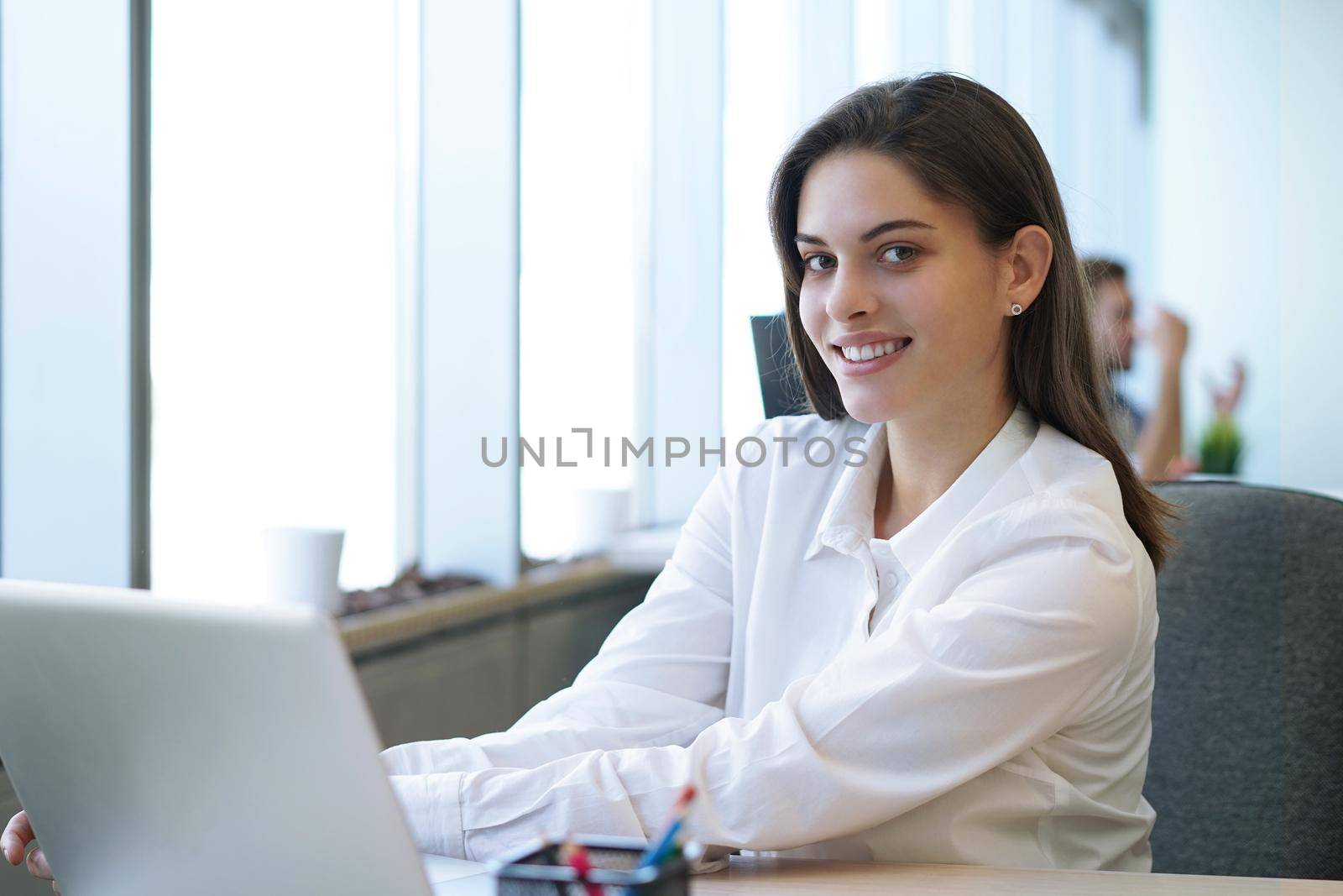 Beautiful business lady is looking at camera and smiling while working in office. by tsyhun