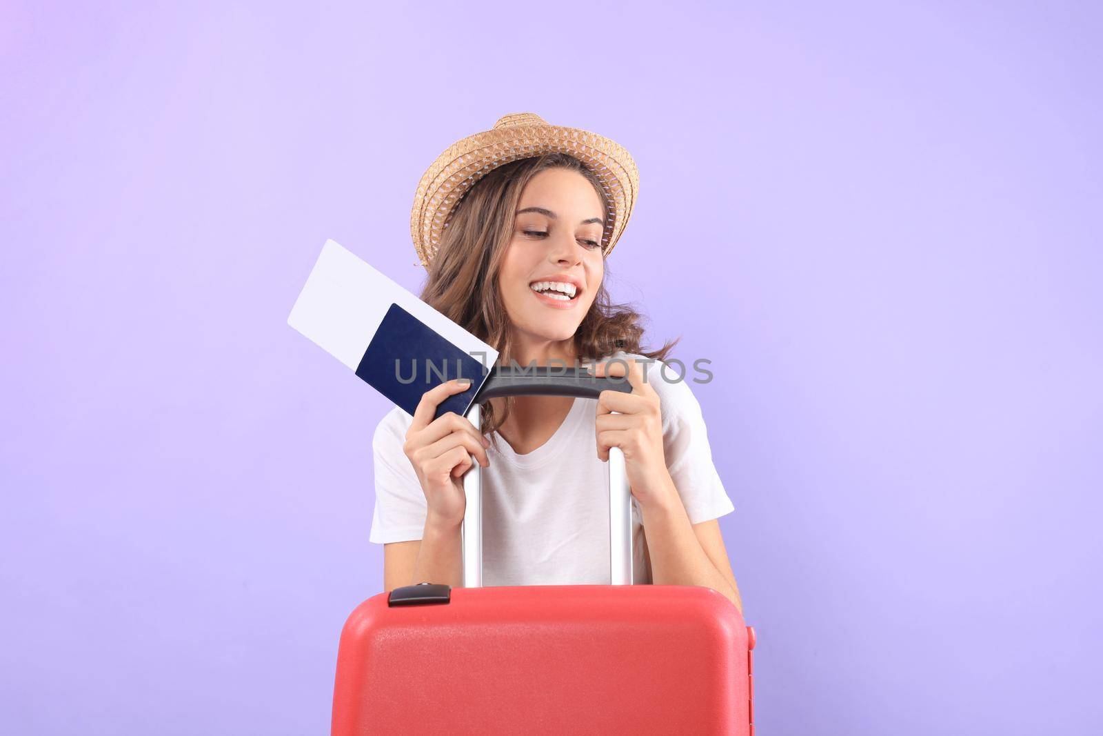 Young tourist girl in summer casual clothes, with sunglasses, red suitcase, passport isolated on purple background