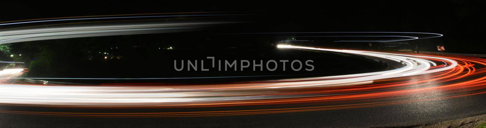 vegicle light trails in night on busy countryroad curve  long exposure