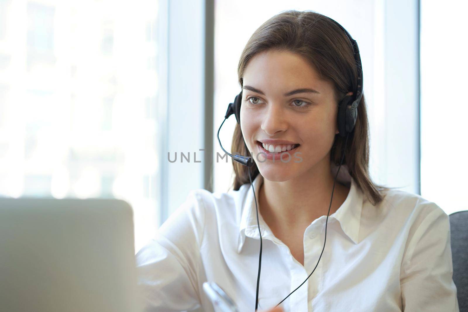 Female customer support operator with headset and smiling.