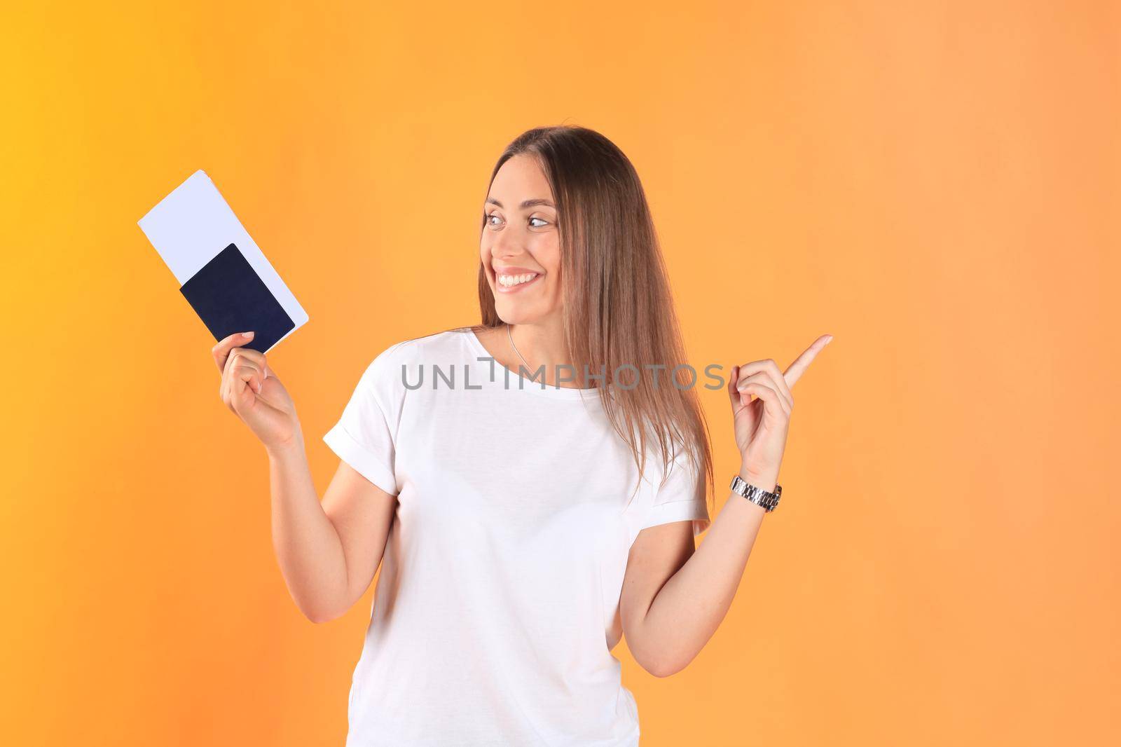 Excited young woman tourist standing isolated on yellow background holding passport with tickets, plastic credit card.