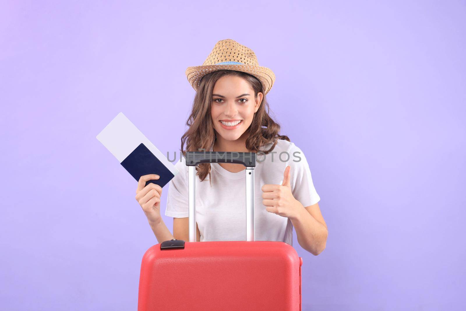 Young tourist girl in summer casual clothes, with sunglasses, red suitcase, passport isolated on purple background