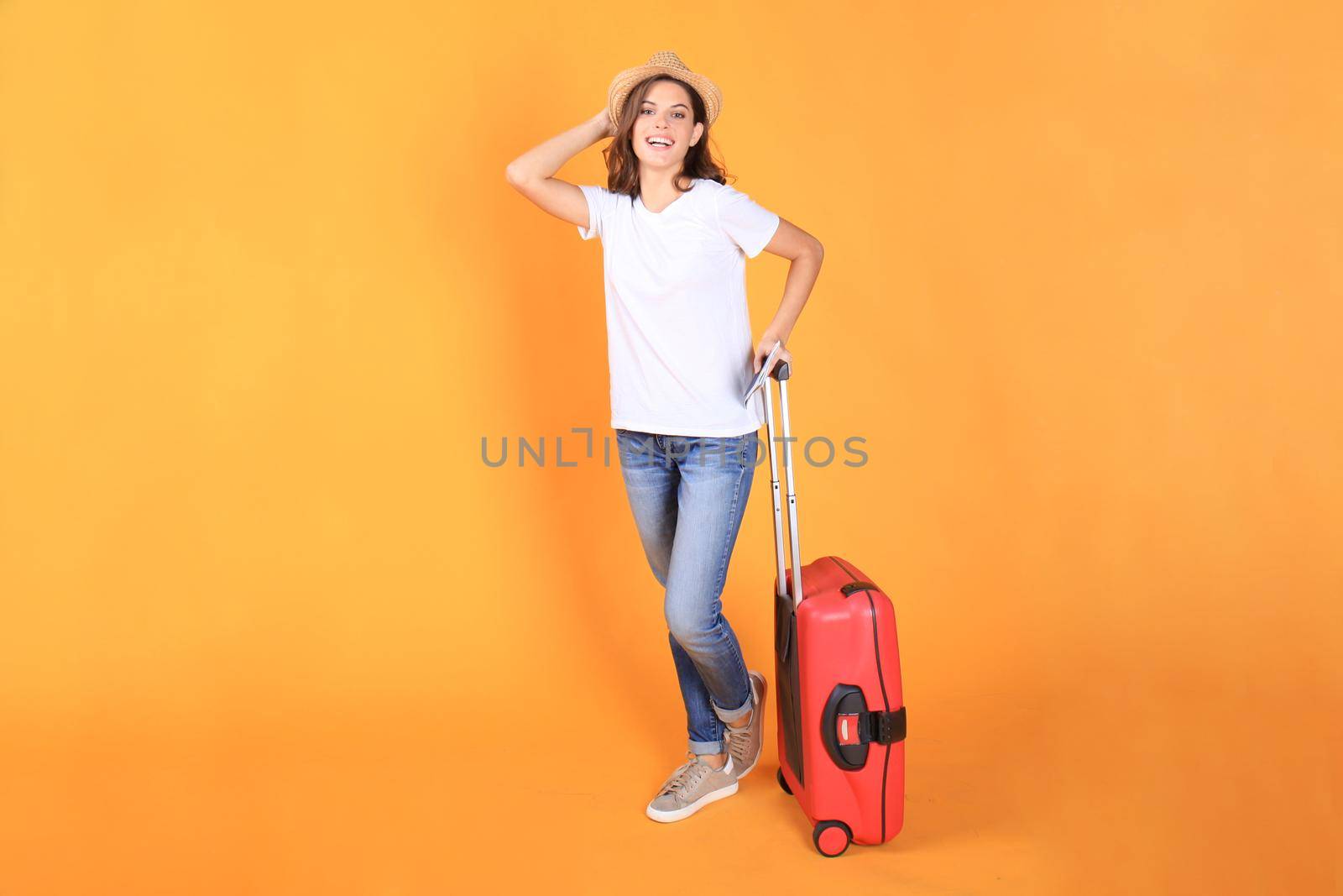 Young tourist girl in summer casual clothes, with red suitcase, passport, tickets isolated on beige background