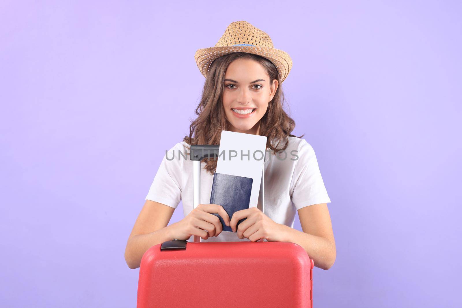 Young tourist girl in summer casual clothes, with sunglasses, red suitcase, passport isolated on purple background