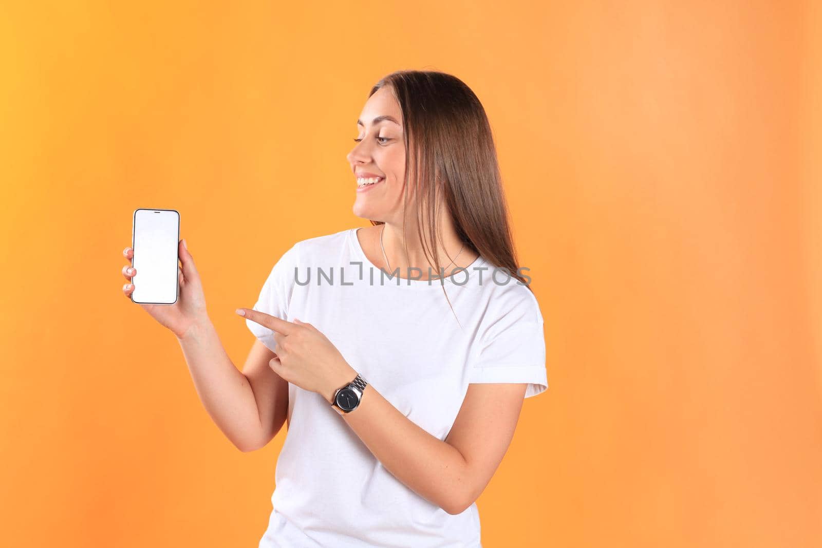 Young woman dressed in basic clothing isolated on yellow background, using mobile phone.