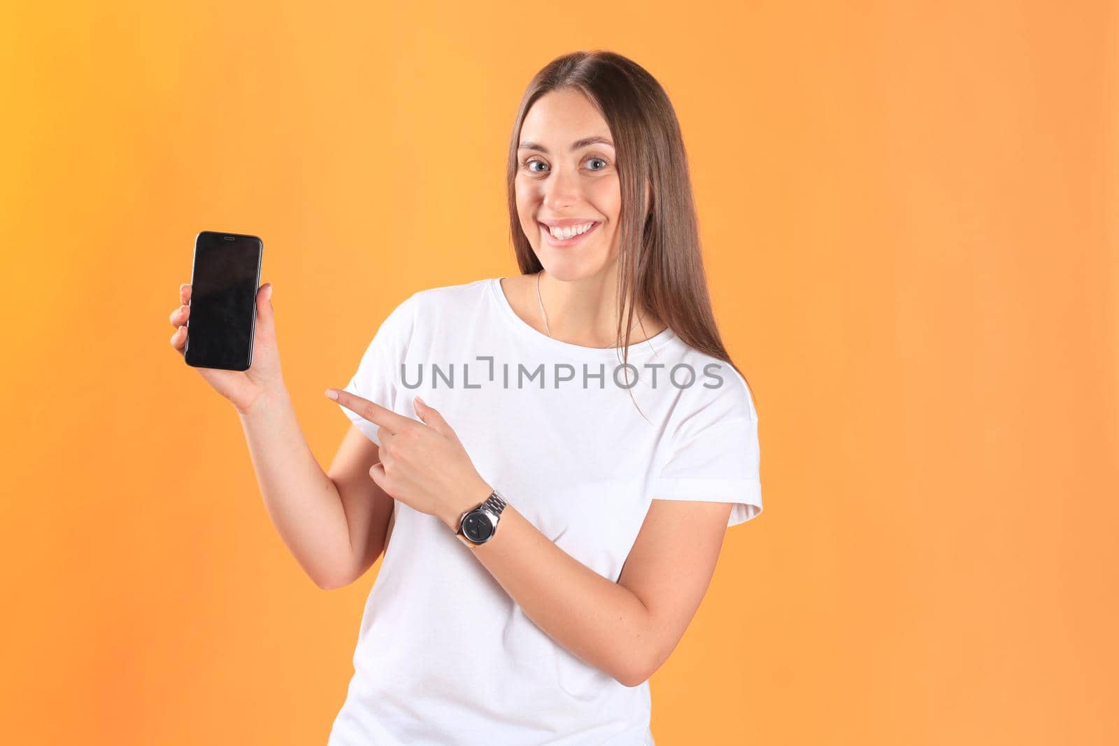 Young woman dressed in basic clothing isolated on yellow background, using mobile phone.