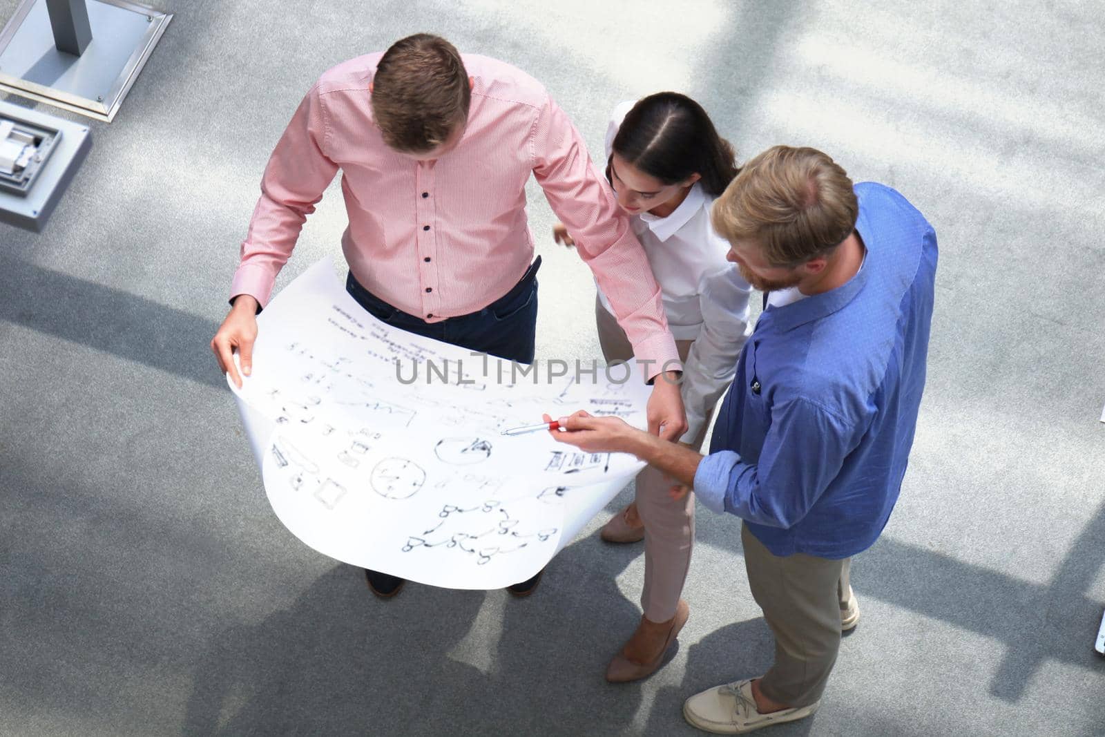Top view of young modern people in smart casual wear discussing business while standing in creative office