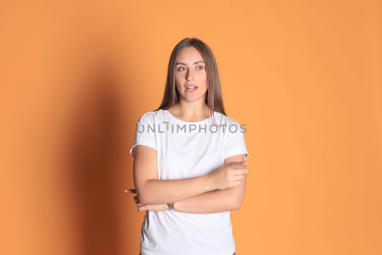 Young woman in basic clothing smiling and pointing finger at copyspace isolated on yellow background.