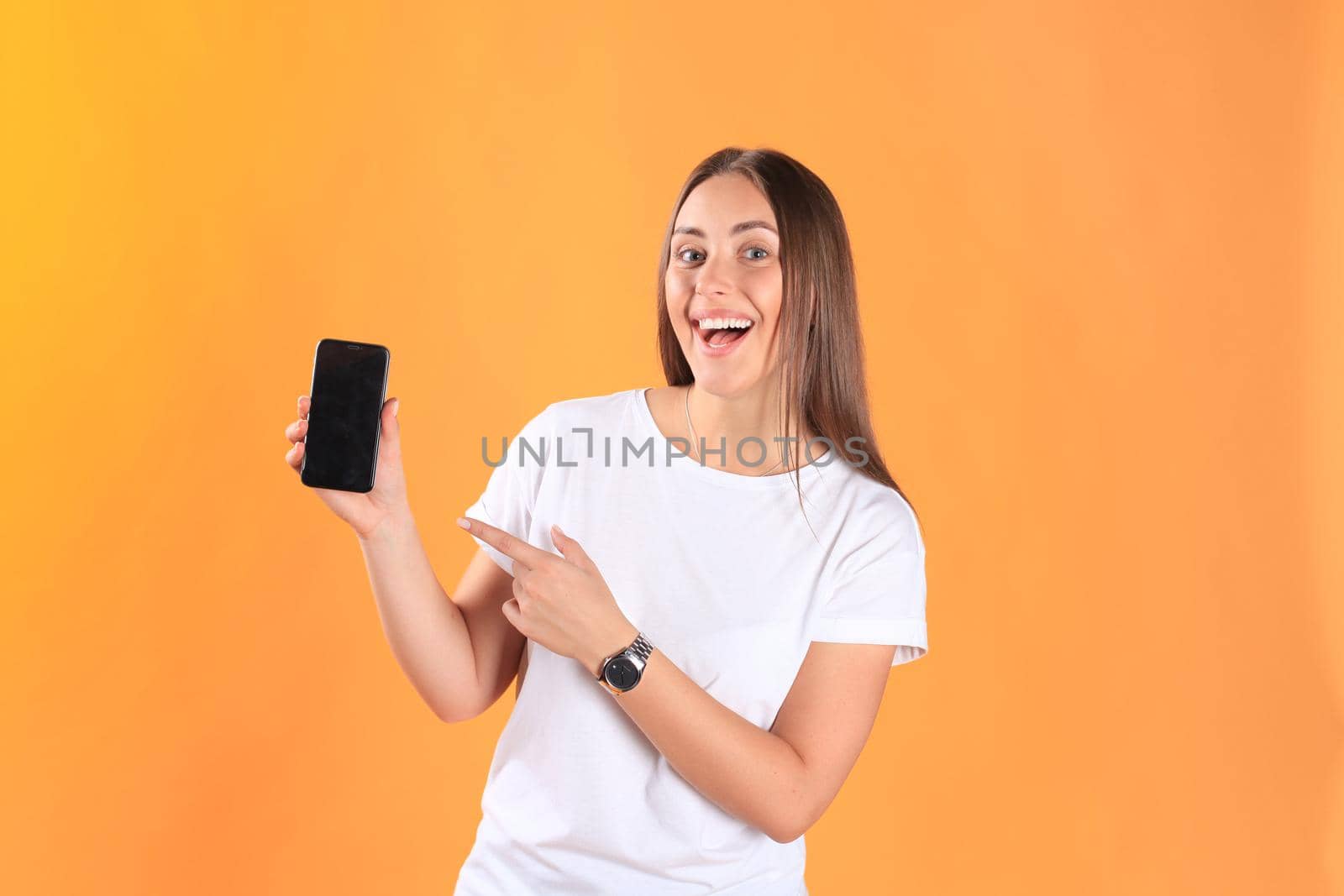 Young woman dressed in basic clothing isolated on yellow background, using mobile phone.