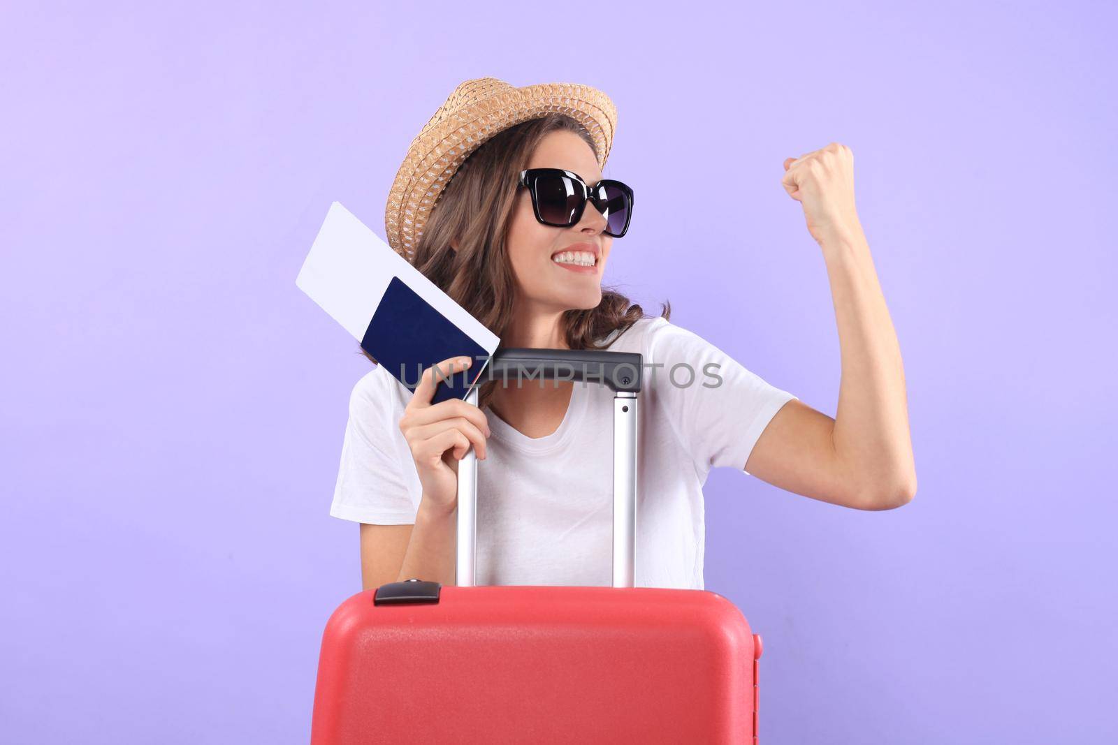 Young tourist girl in summer casual clothes, with sunglasses, red suitcase, passport isolated on purple background