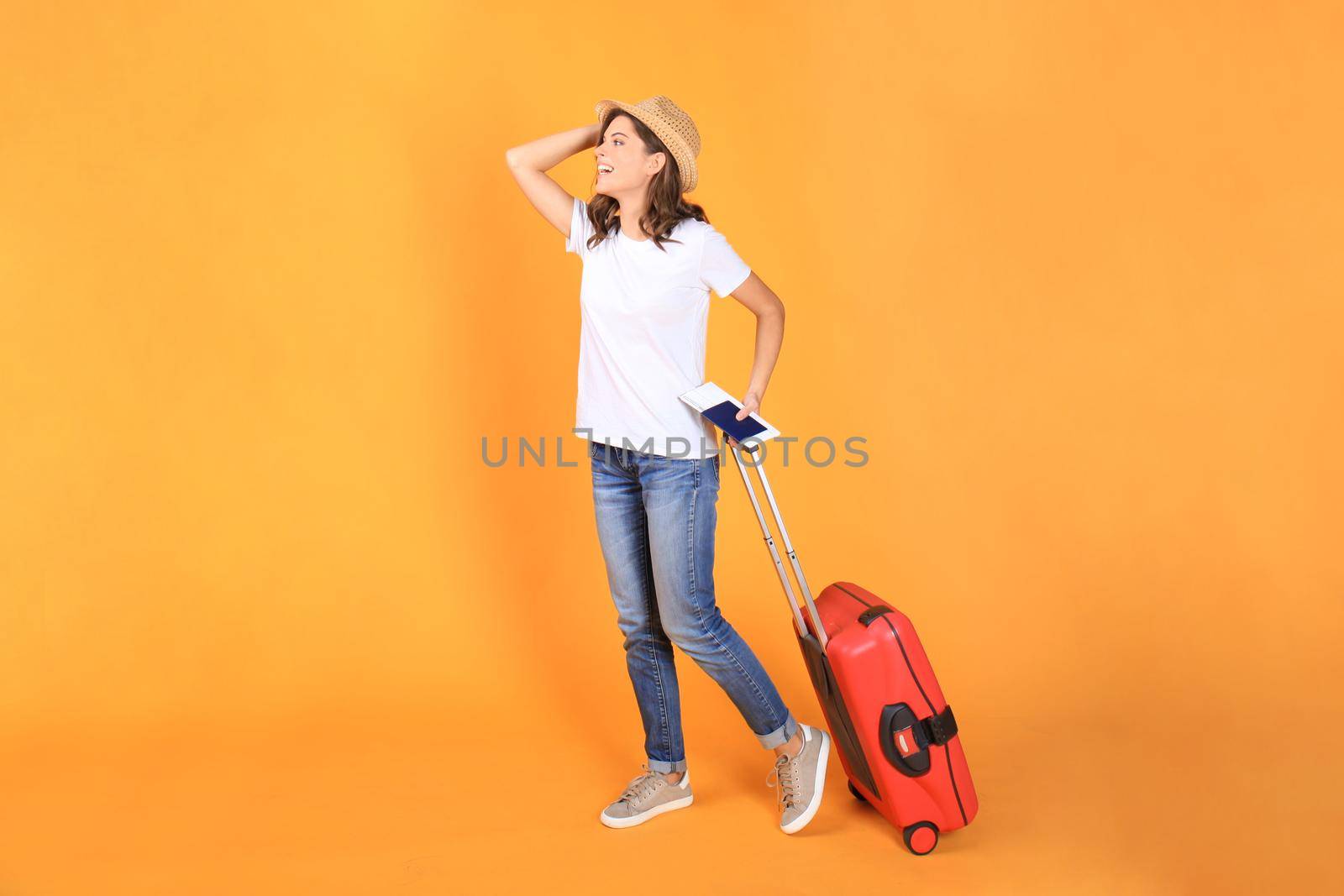 Young tourist girl in summer casual clothes, with red suitcase, passport, tickets isolated on beige background